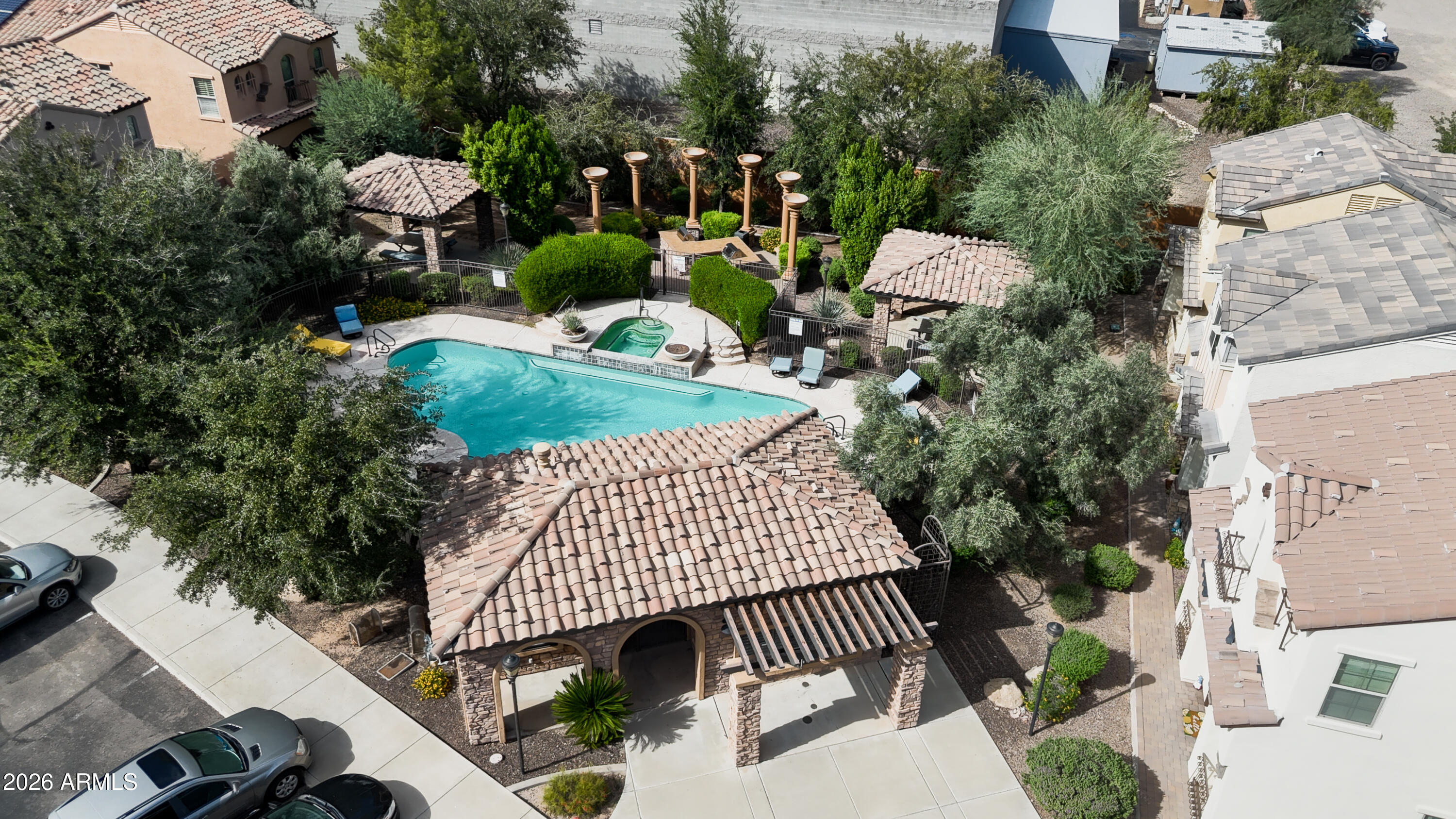 Community pool and spa surrounded by landscaped grounds and tiled-roof shade structures.