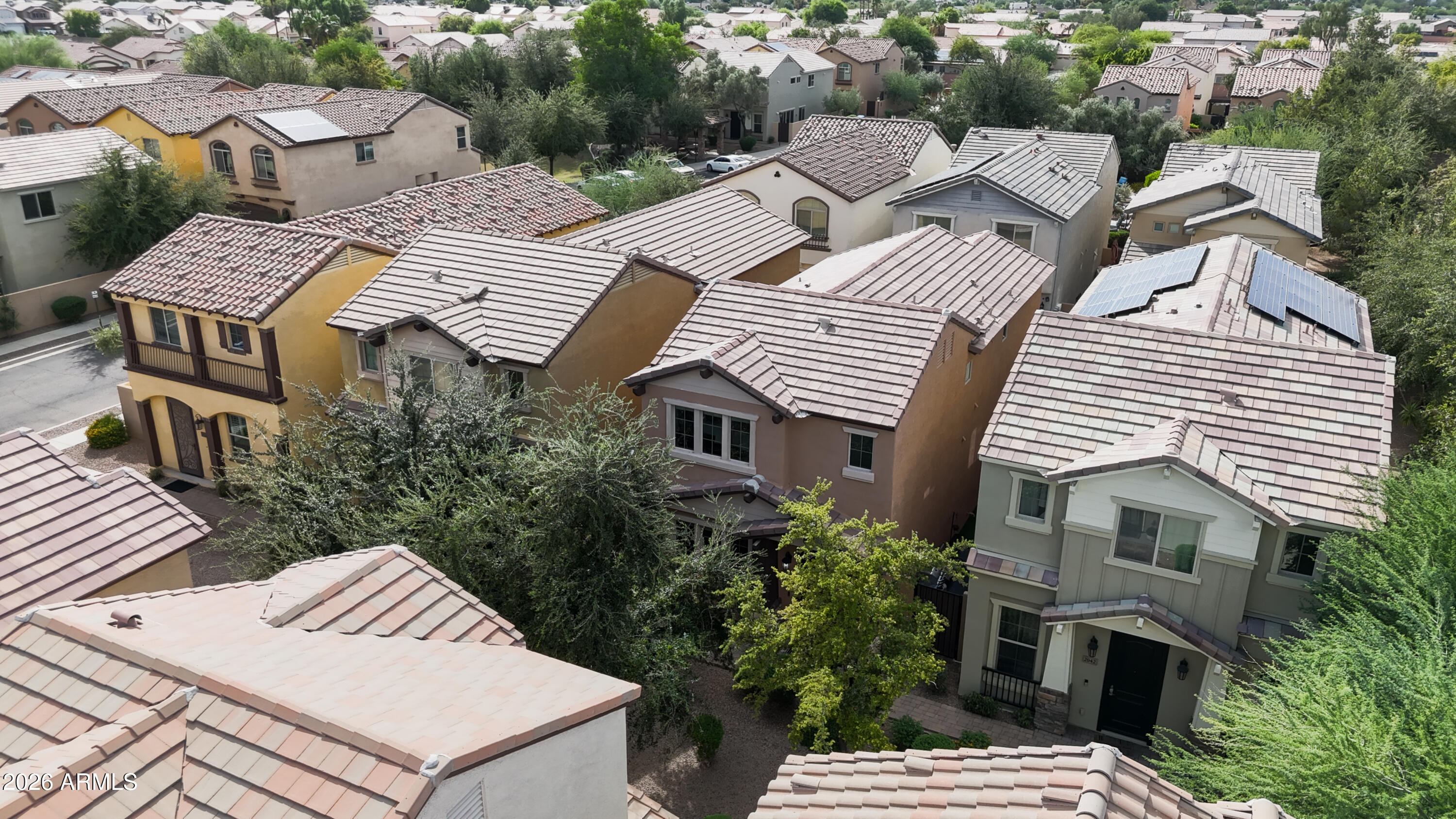 Aerial view of two-story homes with tiled roofs, desert landscaping, and solar panels.