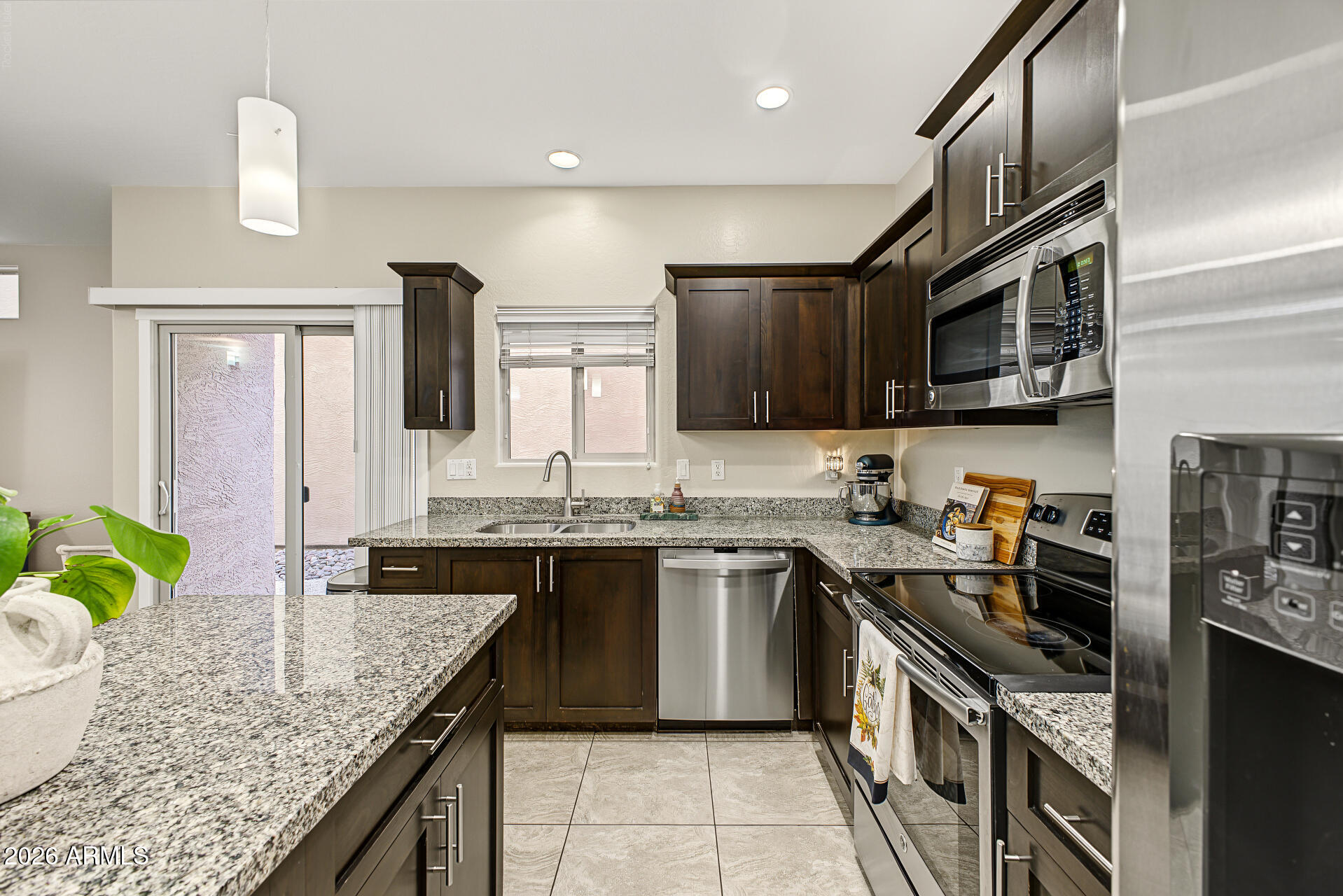 Kitchen with dark wood cabinets, granite counters, stainless steel appliances, and a large island.