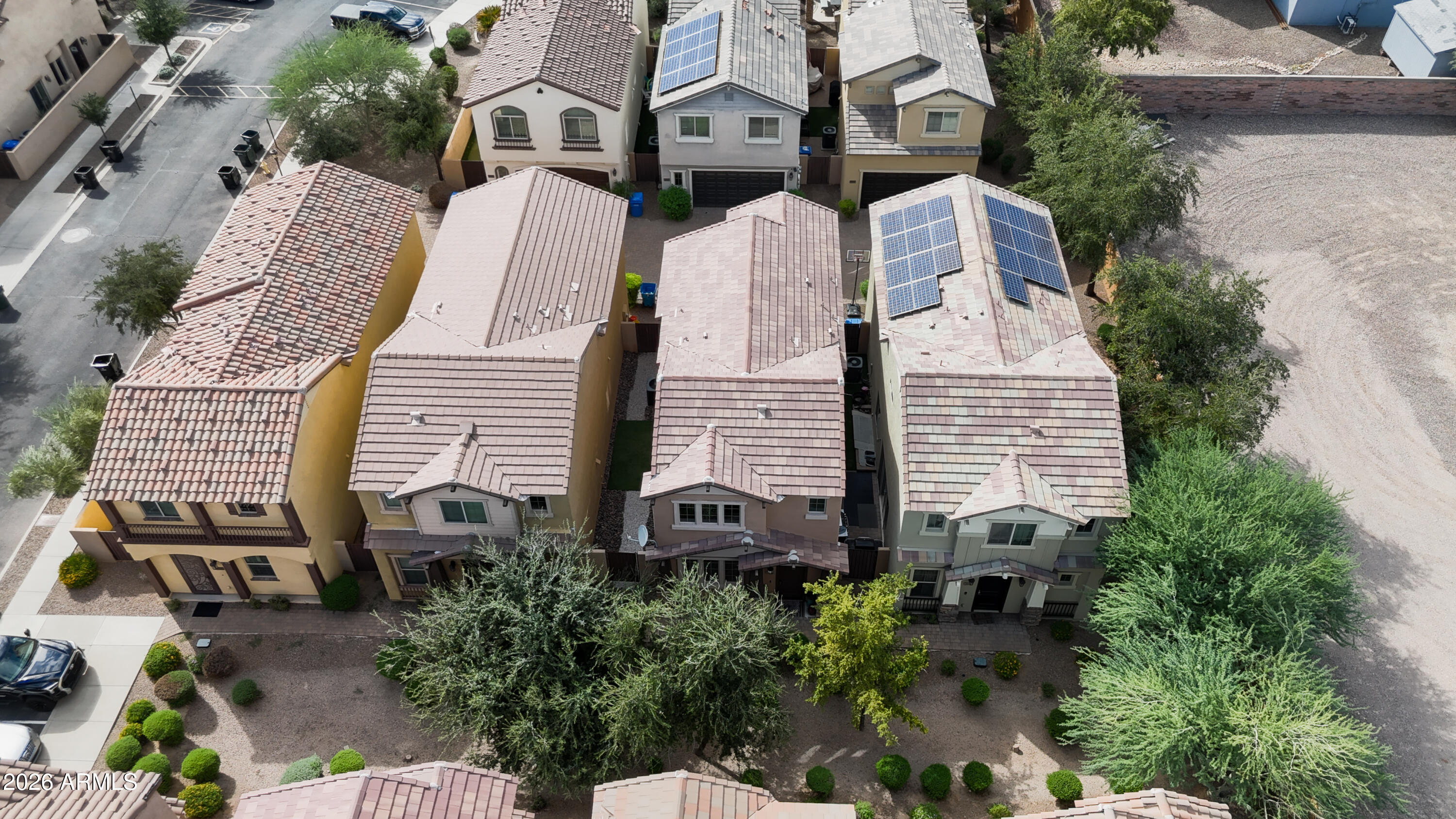 Aerial view of closely spaced homes, with solar panels on several tiled roofs.