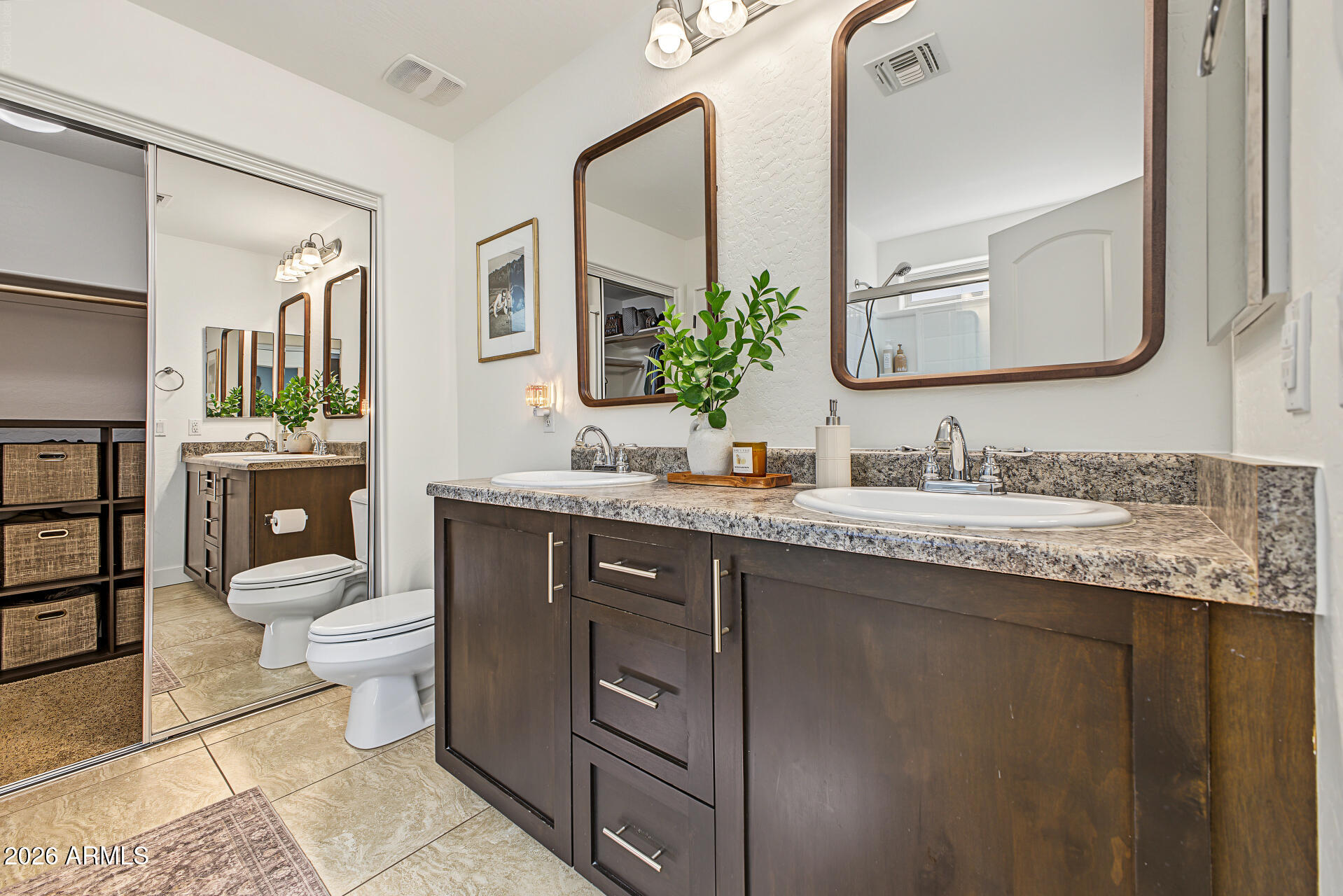 Bathroom with a double-sink dark wood vanity, granite counters, and large framed mirrors.