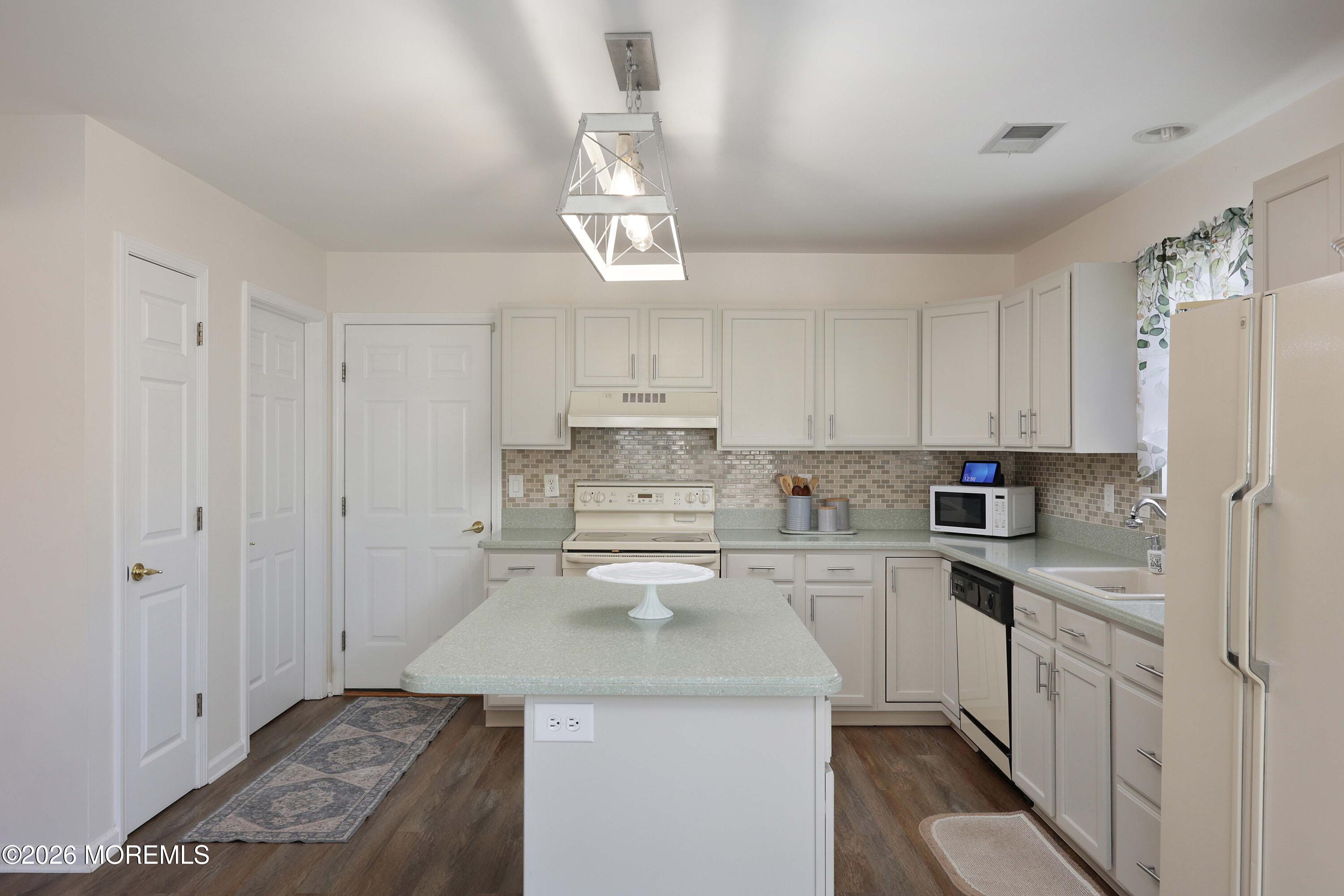 Kitchen with white cabinetry, tiled backsplash, and a central island.
