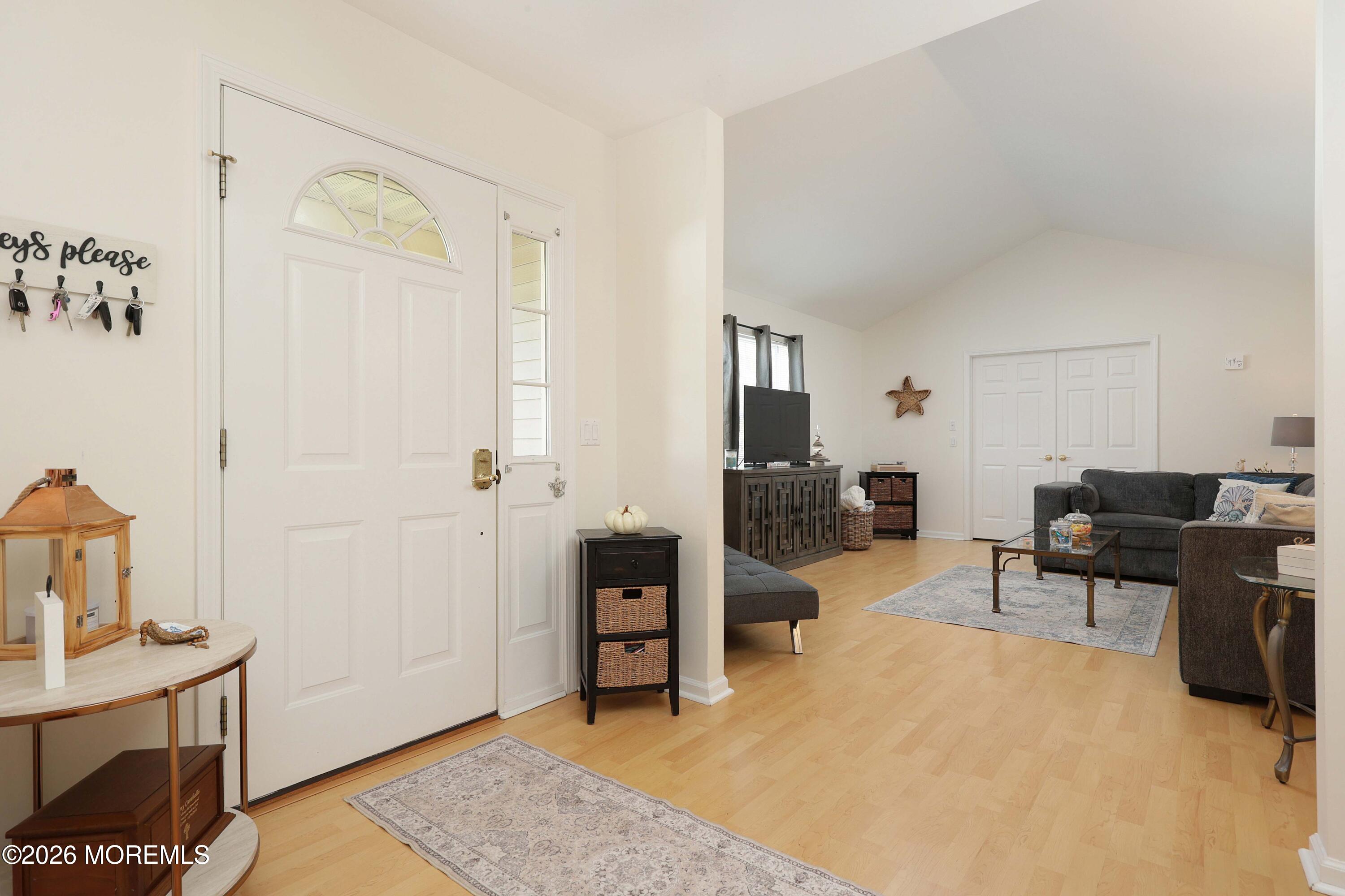 Entryway with a white semicircular-window front door opening to a living room with gray sofas.