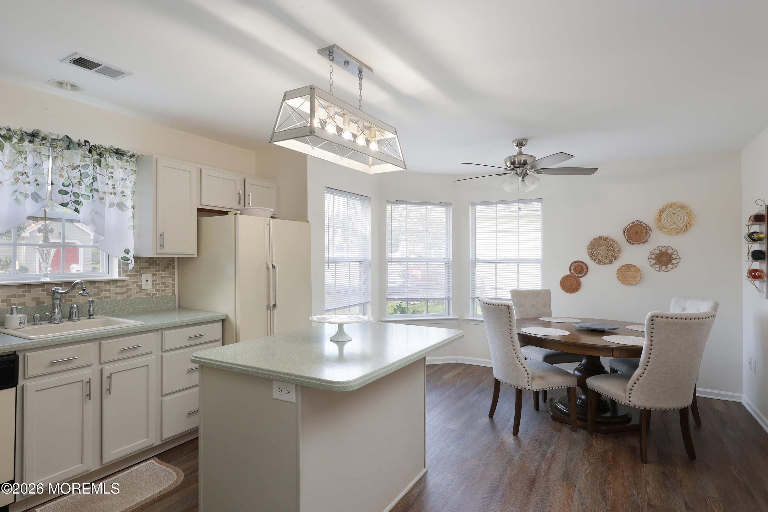 Open-plan kitchen and dining area with a large island and round table beside three windows.