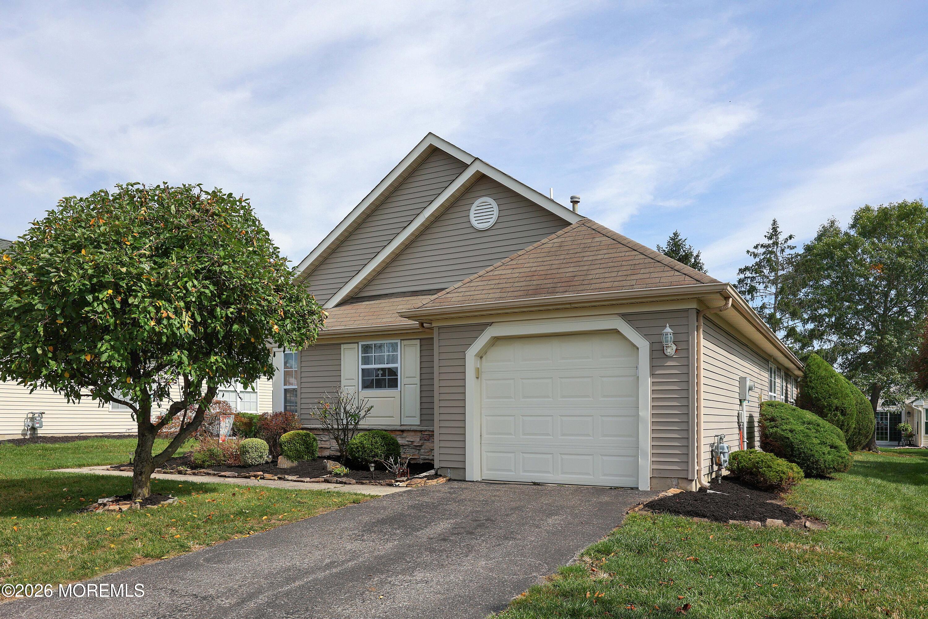 Home exterior with a white garage door, paved driveway, and landscaped front yard.