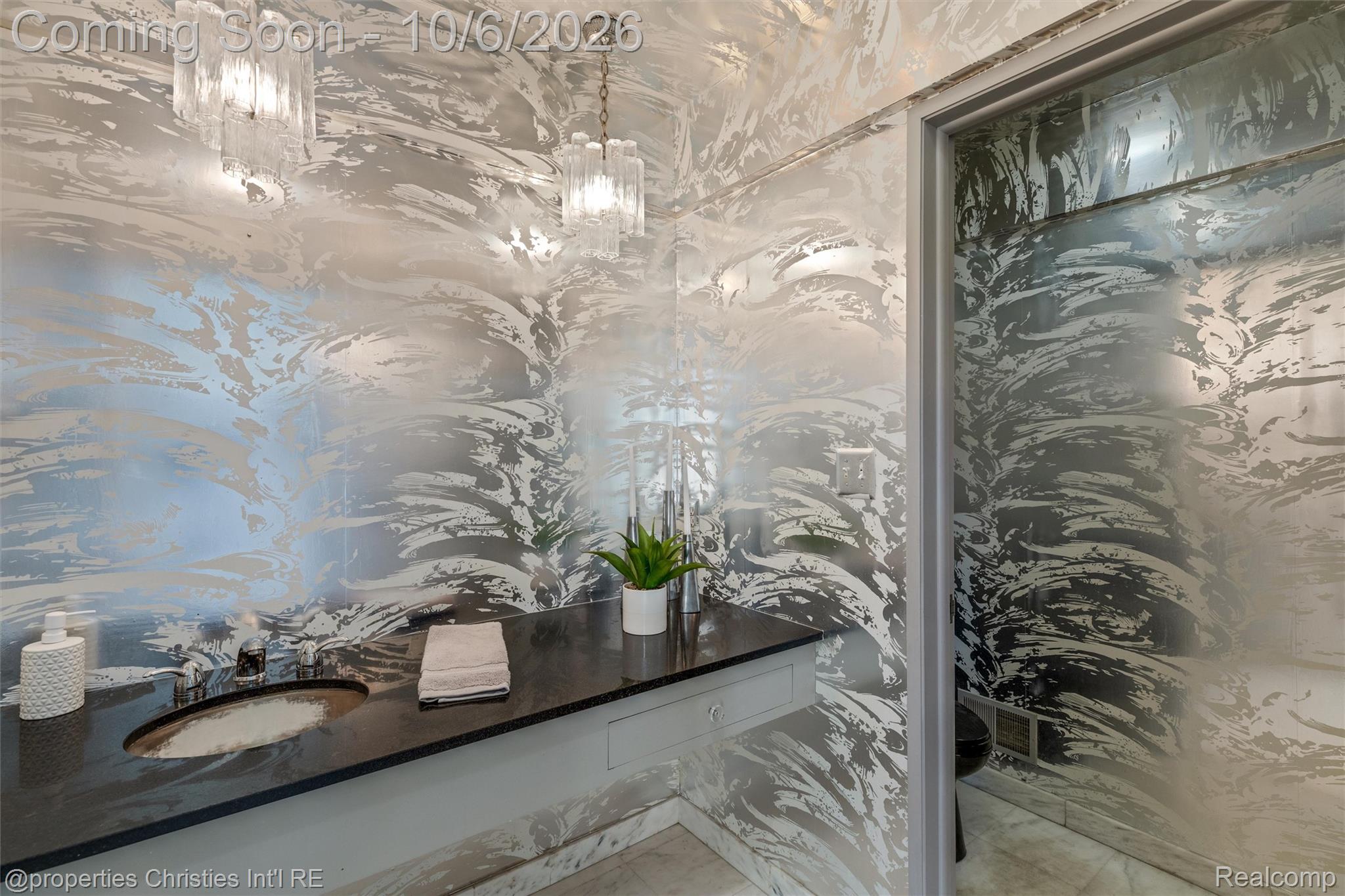 Bathroom vanity with an oval sink, dark countertop, and striking abstract-patterned walls.