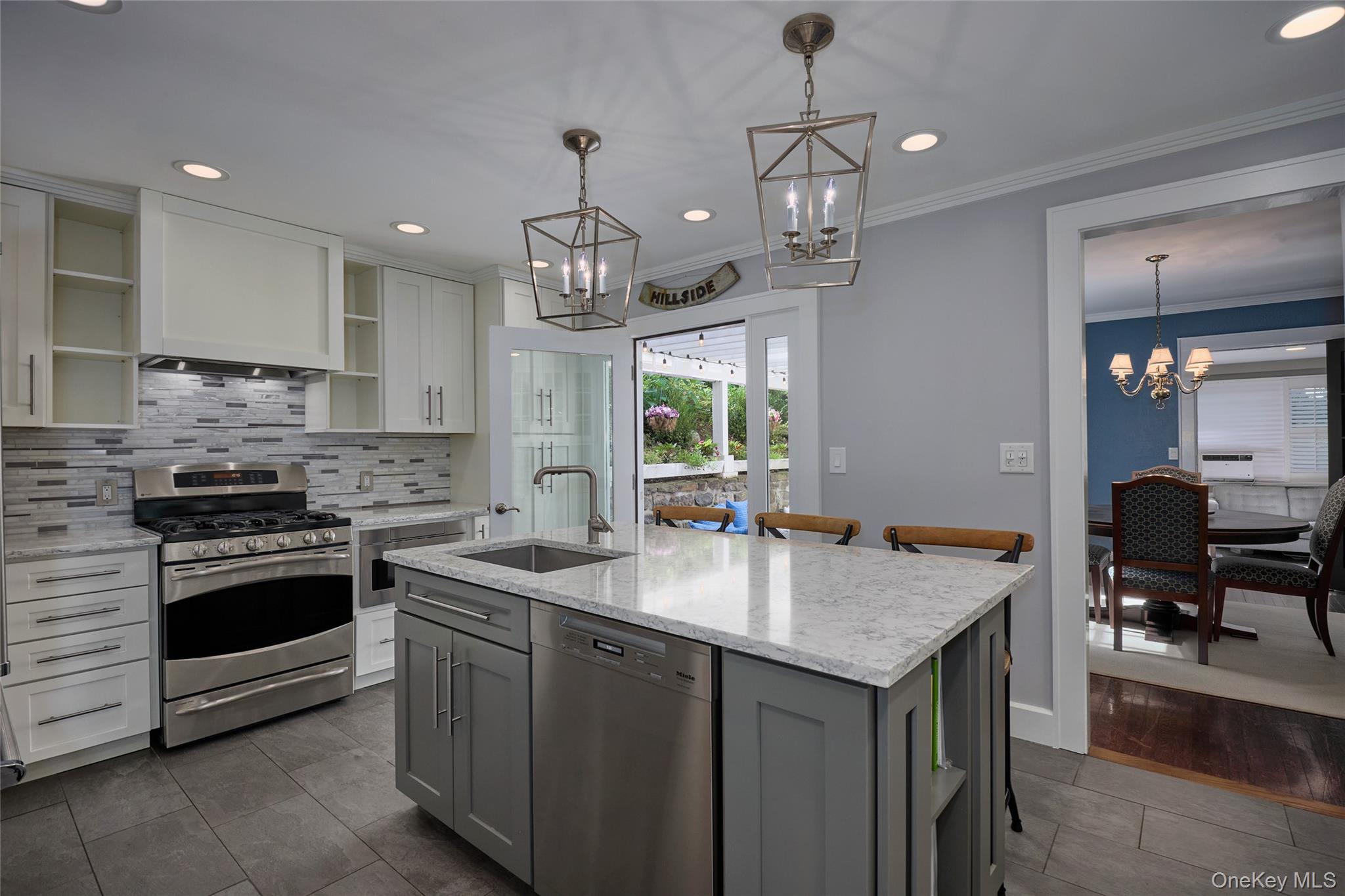Renovated kitchen with a large gray island, marble-patterned counters, stainless steel range, and garden doors.