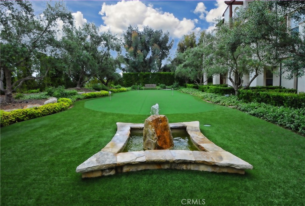Landscaped courtyard with a stone fountain, putting green, and mature trees.
