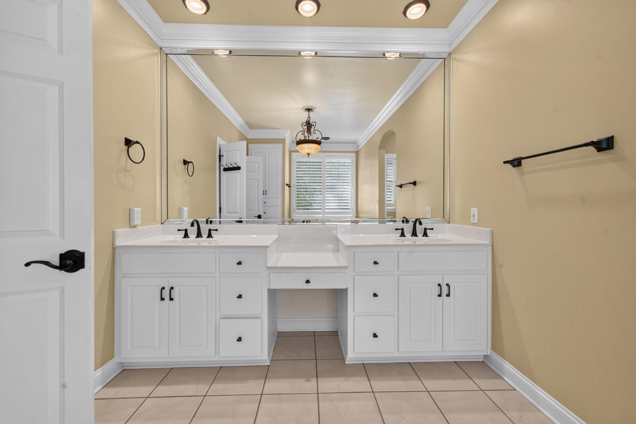 Bathroom with twin white vanities, a large mirror, and a shuttered window.