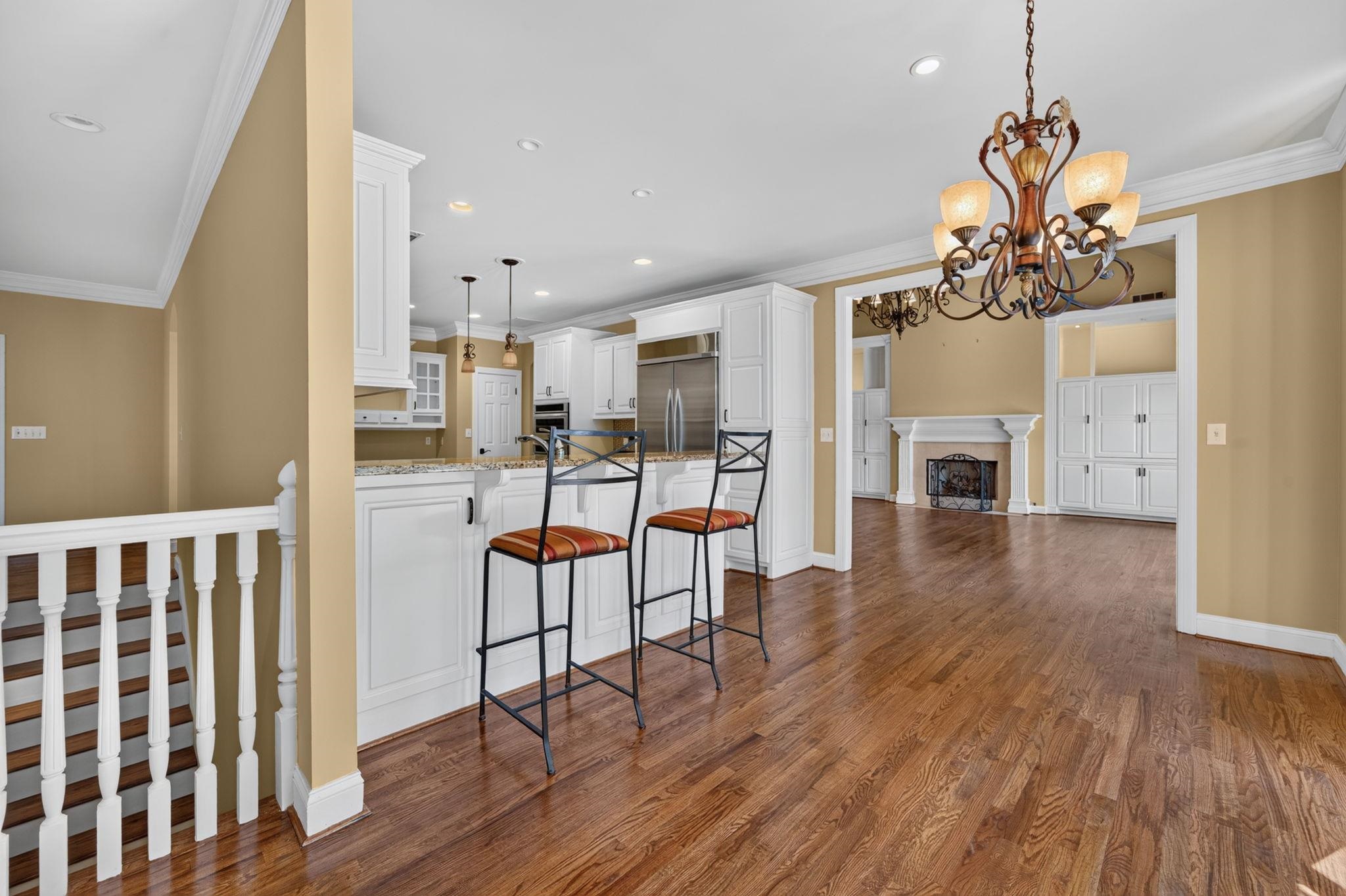 Kitchen breakfast bar with two stools opens to a living area with a fireplace.