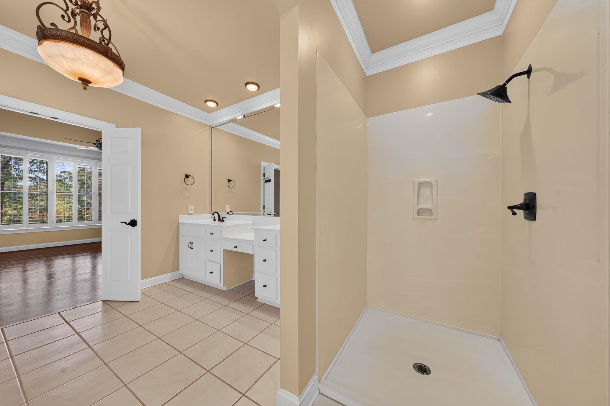 Bathroom with a tiled walk-in shower and white double vanity beside a large mirror.