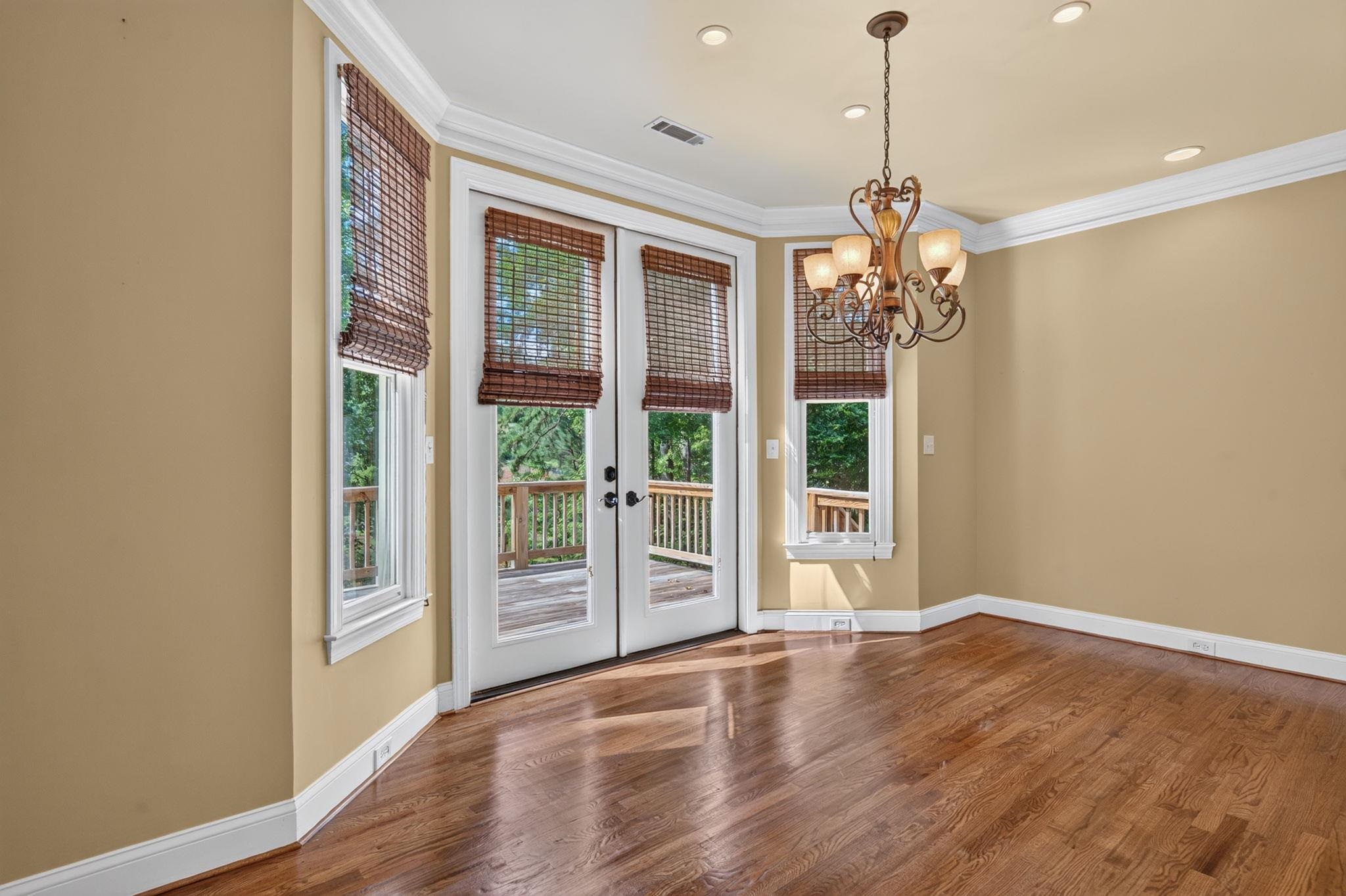 Empty dining room with hardwood floors, a chandelier, and French doors opening to a deck.