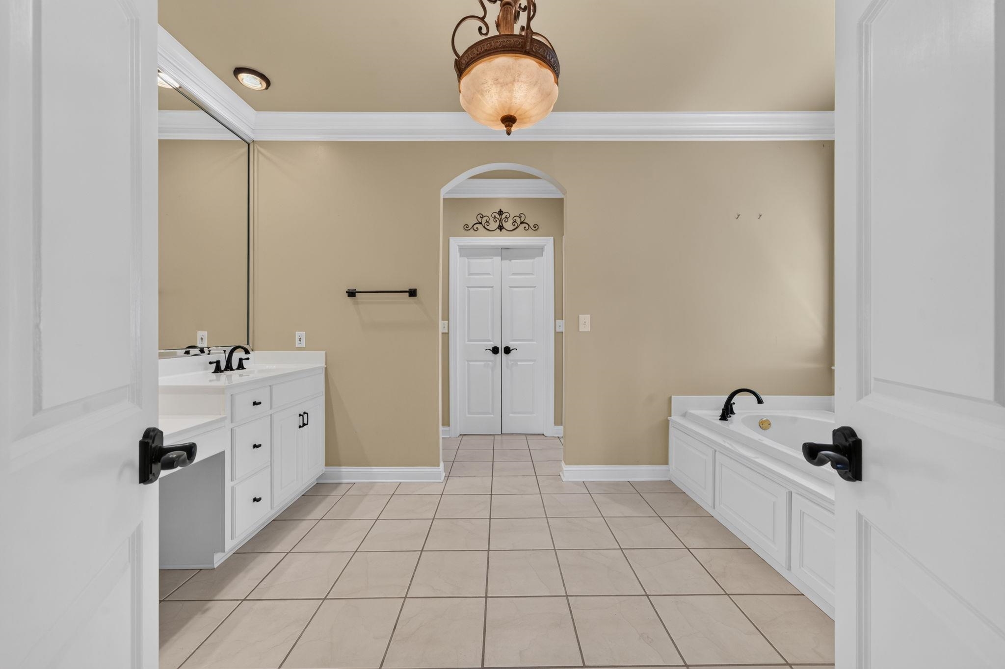 Bathroom with a white vanity, built-in bathtub, and tiled floor.