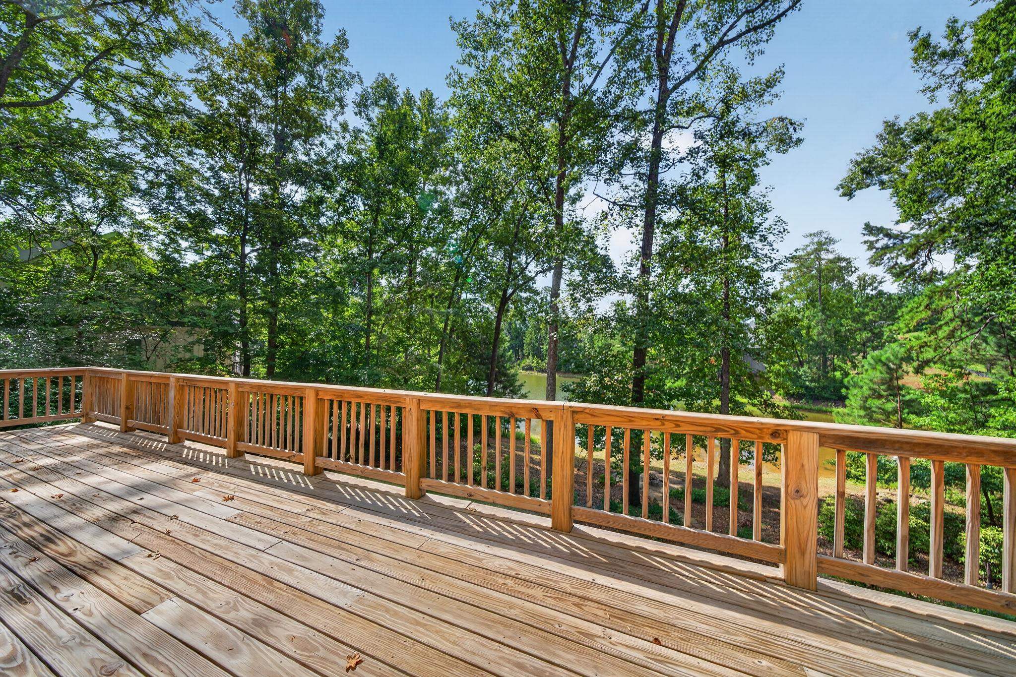 Wood deck overlooking a pond through leafy trees.