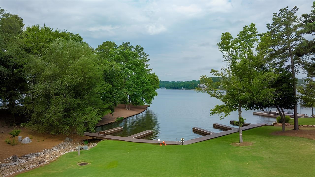 Lakefront shoreline with private docks, mature trees, and a broad green lawn.