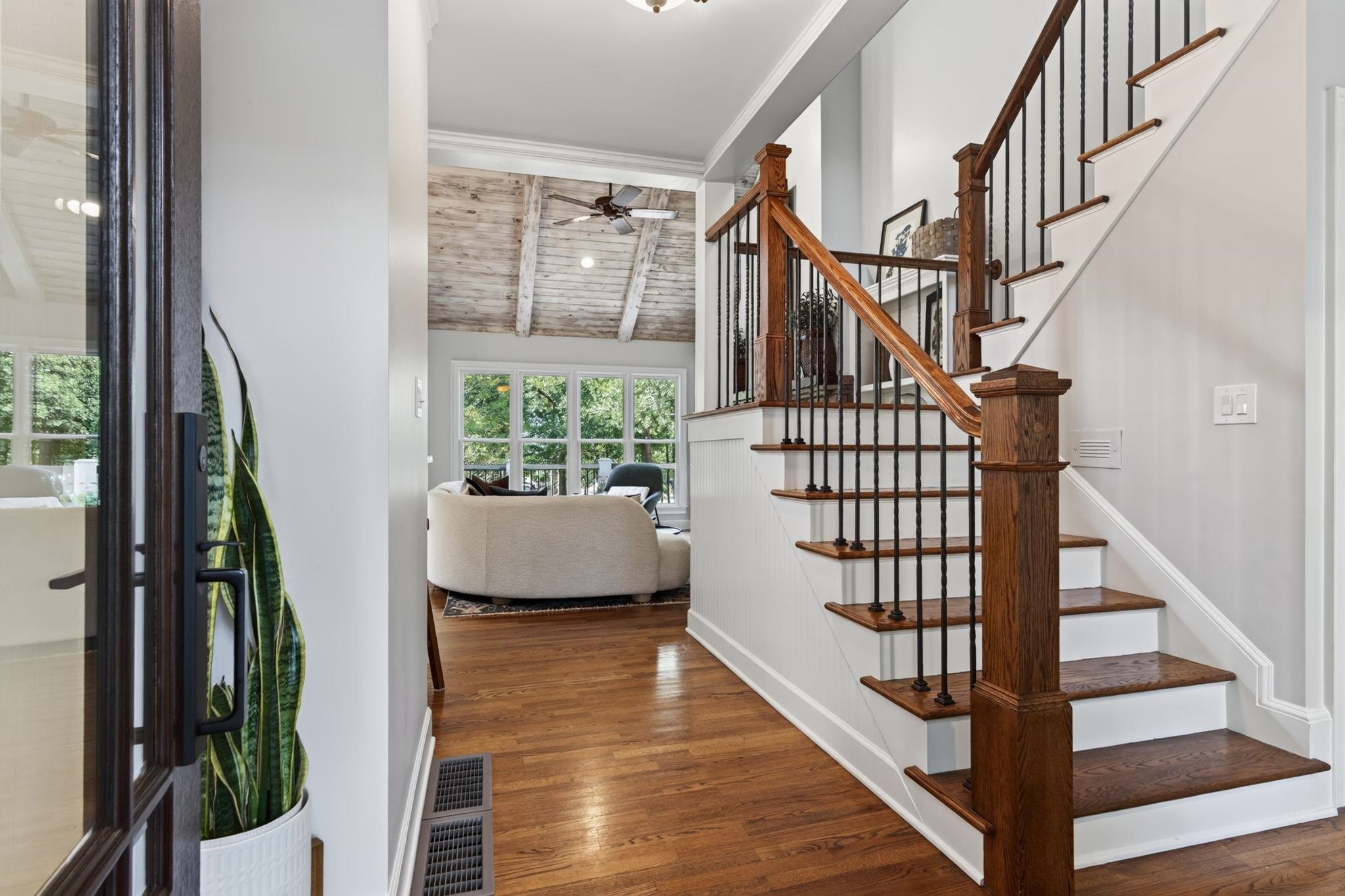 Foyer with a wood-and-iron staircase, hardwood floors, and a view into the living room.