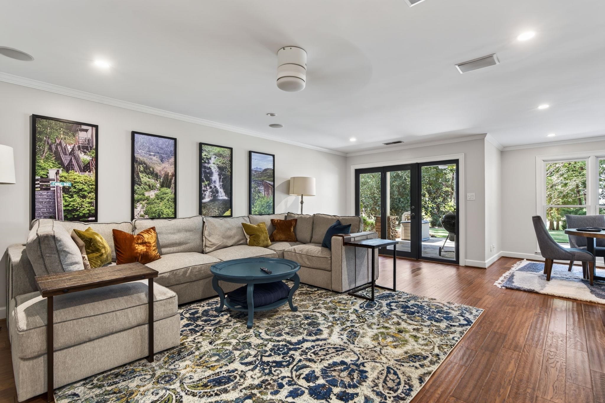 Furnished living room with a sectional sofa, patterned rug, and black-framed doors opening to a garden.