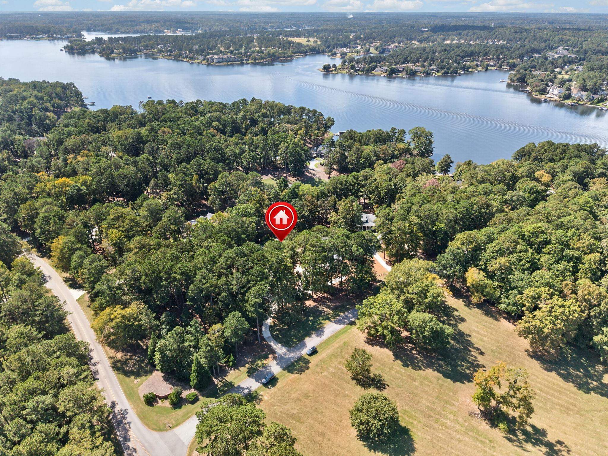 Aerial view of a wooded property near the lake, marked by a red home pin.