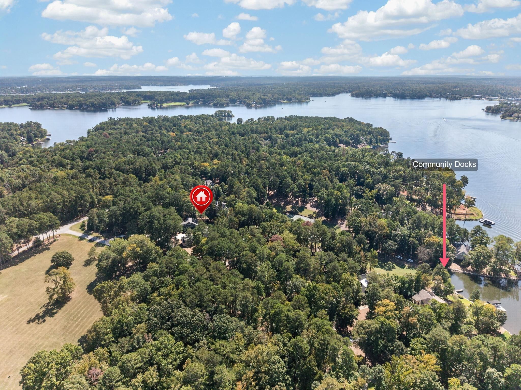 Aerial view of a wooded lakeside neighborhood, with the home marked near community docks.