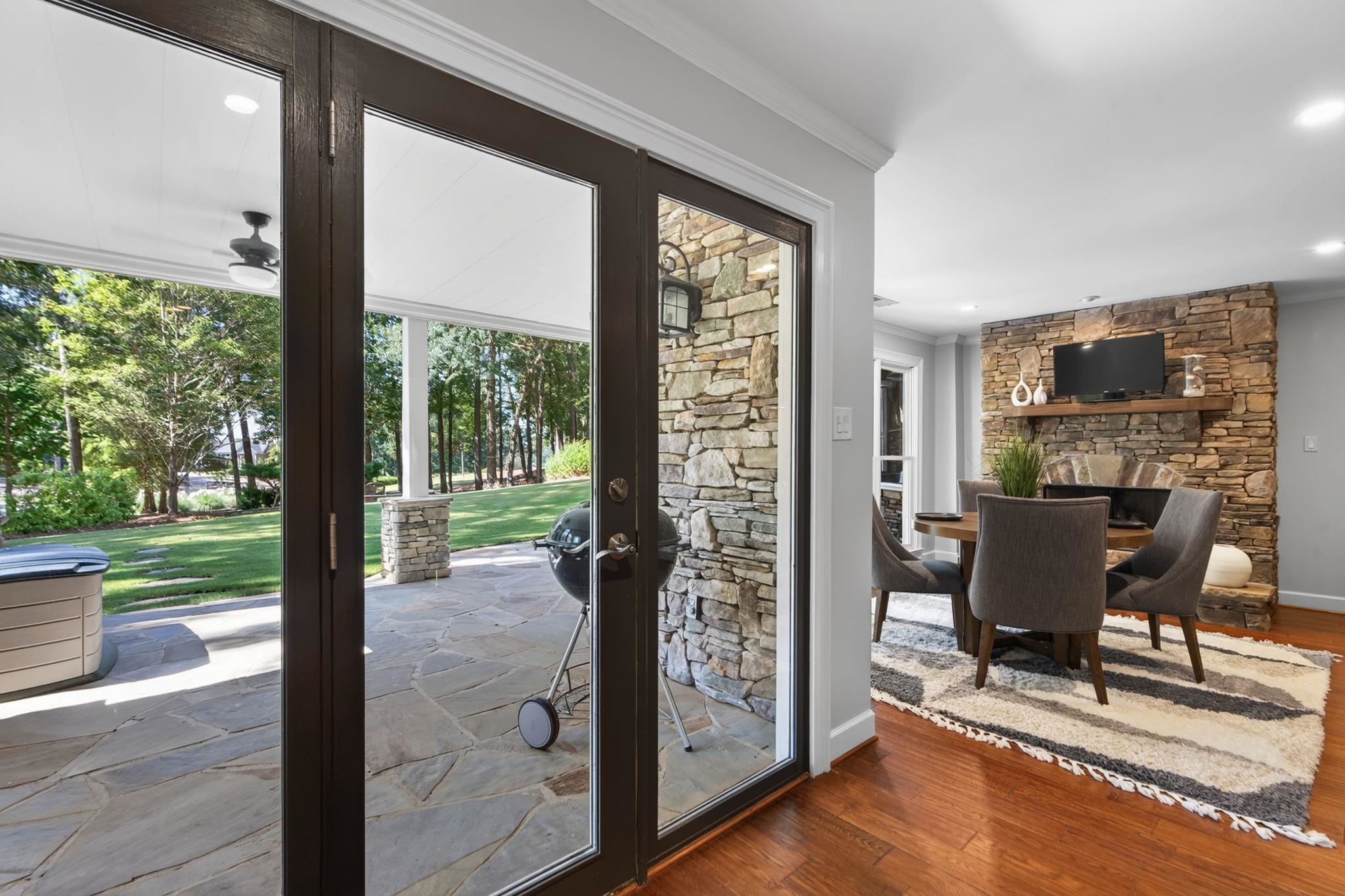 Dining room with a stone fireplace and glass doors opening to a stone patio.
