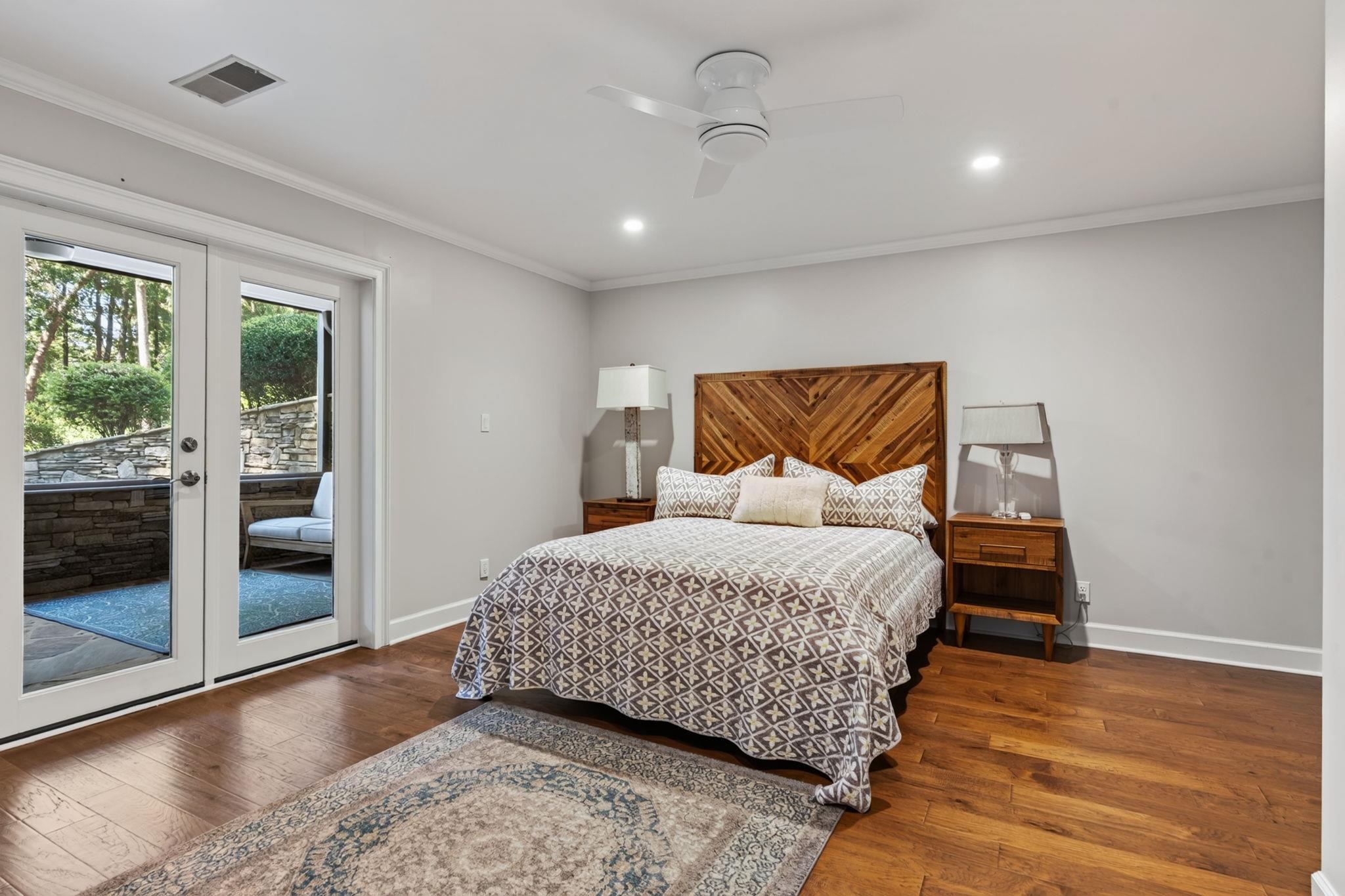 Bedroom with a geometric wood headboard and glass doors opening to a stone-walled patio.