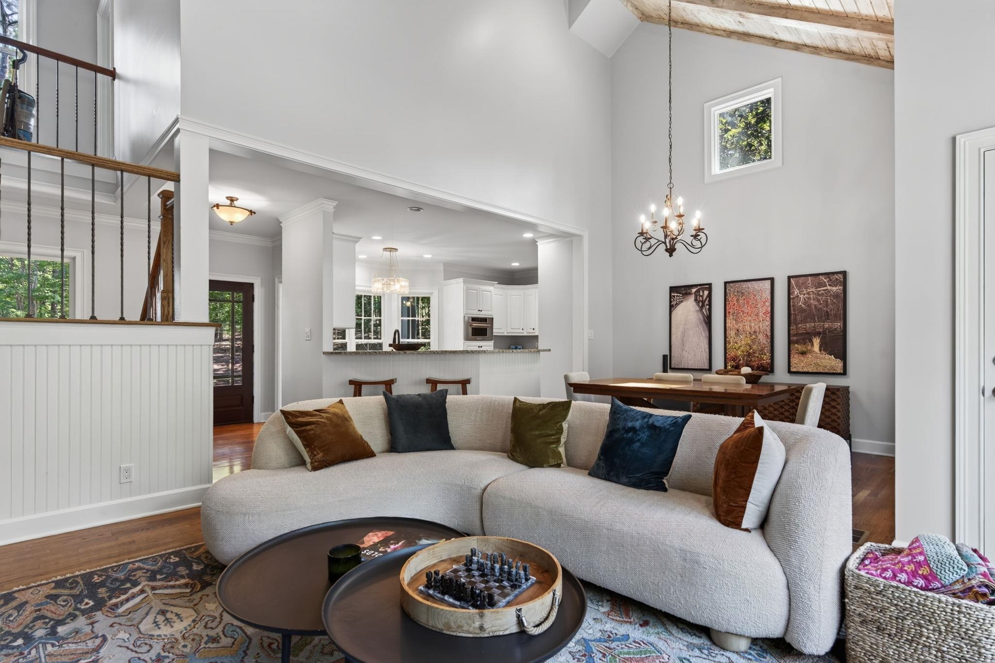 Living room with a curved sectional sofa, high ceilings, and an open kitchen and dining area.