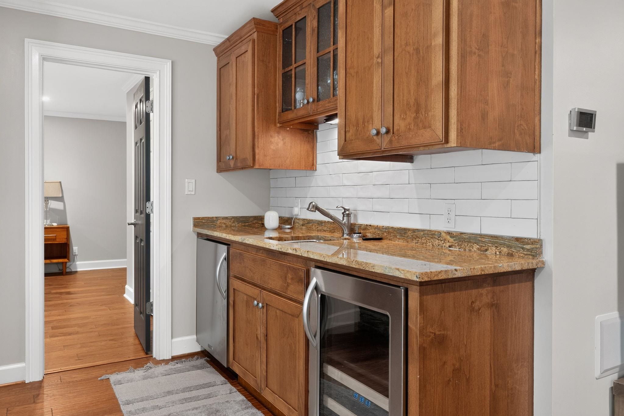Kitchen with warm wood cabinets, granite countertops, white tile backsplash, and stainless steel appliances.
