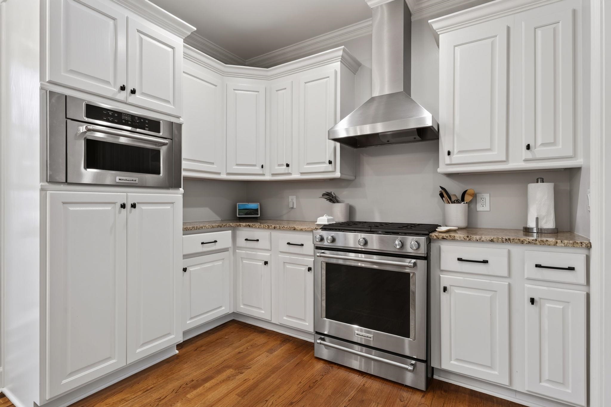 Kitchen with white cabinetry, granite counters, and stainless steel double ovens and range.