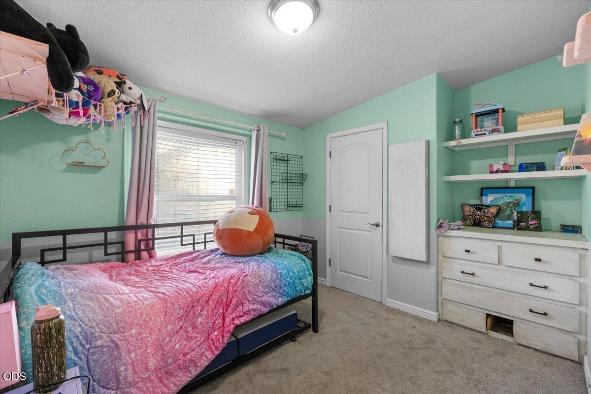 Bedroom with mint-green walls, a black metal bed, a colorful quilt, and white shelving.