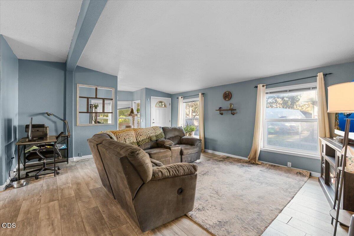 Living room with a large sectional sofa, blue-gray walls, and wide curtained windows.
