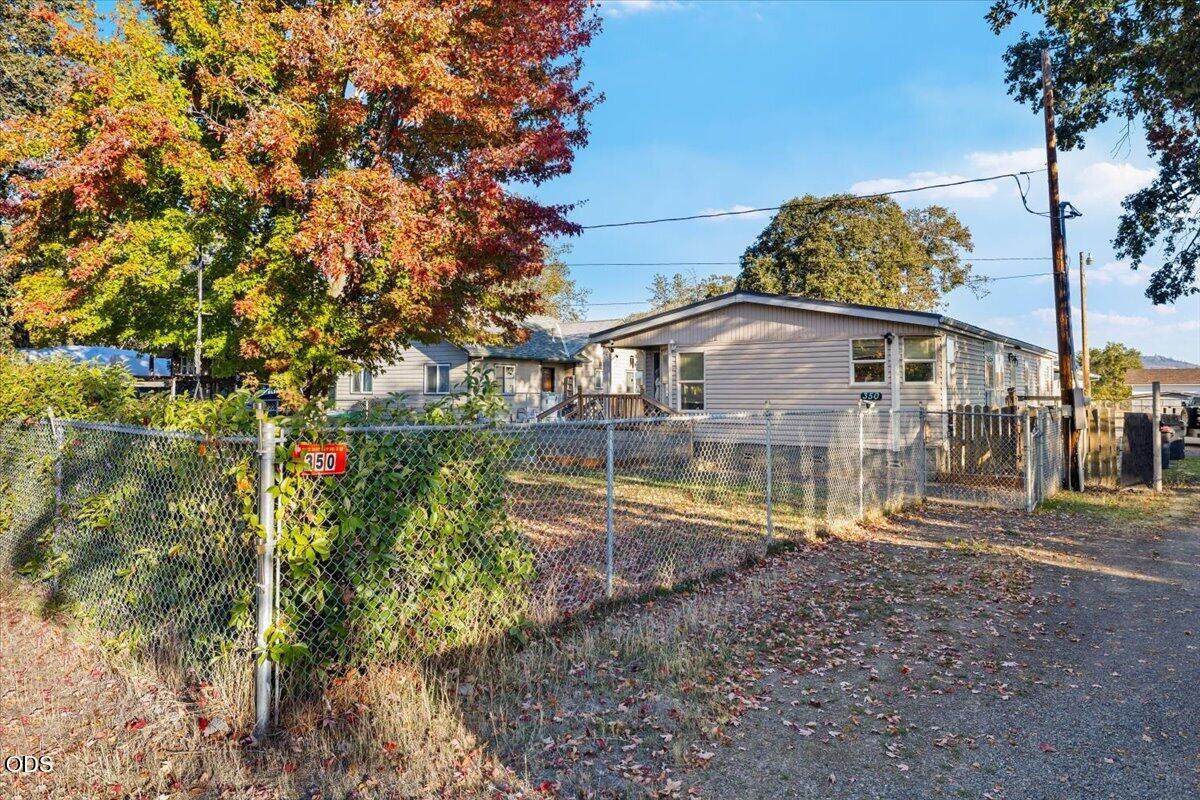 Single-story home behind a chain-link fence, with autumn foliage and the number 350 on the gate.