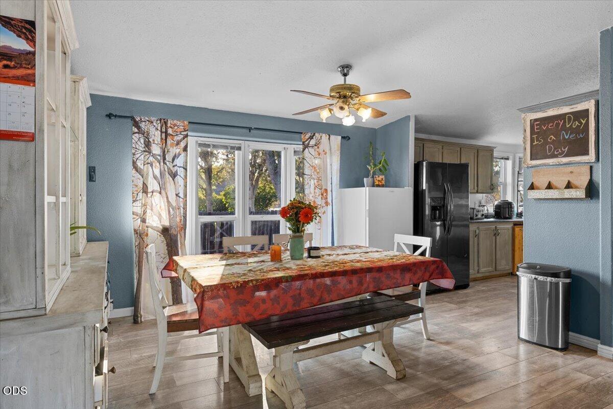 Dining area with a floral-covered table and bench beside a kitchen with wood-tone cabinets.