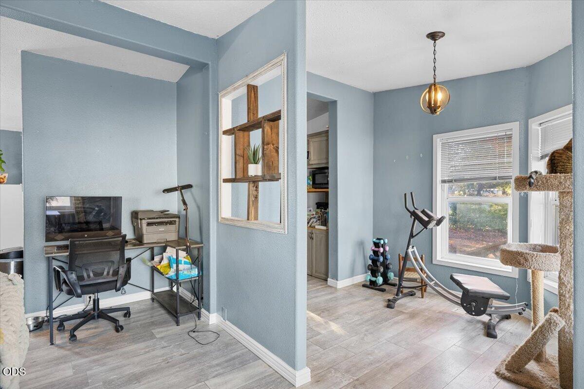 Home interior with a compact office adjoining an exercise area, both with blue walls and gray flooring.