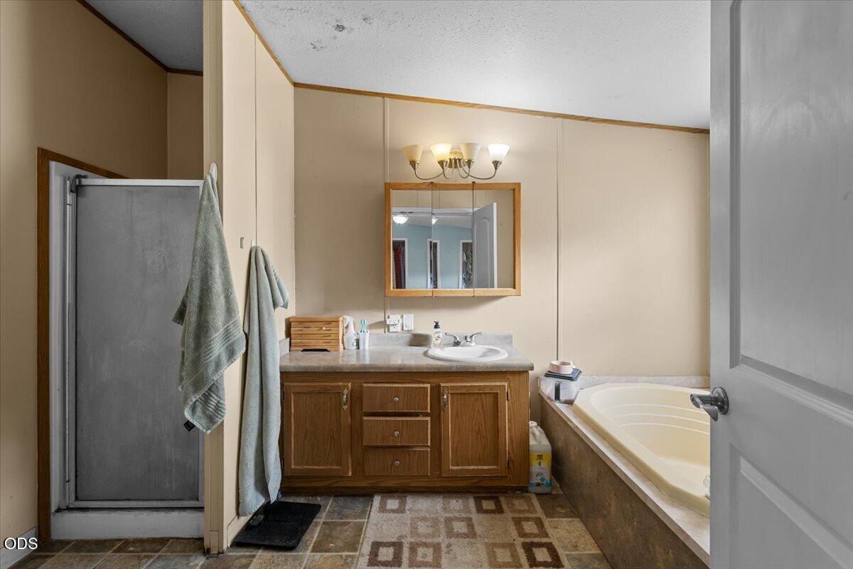 Bathroom with a built-in tub, separate shower stall, and wood vanity.