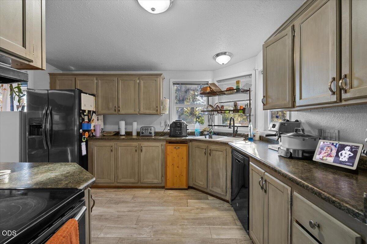 U-shaped kitchen with wood-tone cabinets, dark countertops, and a sink beneath a window.