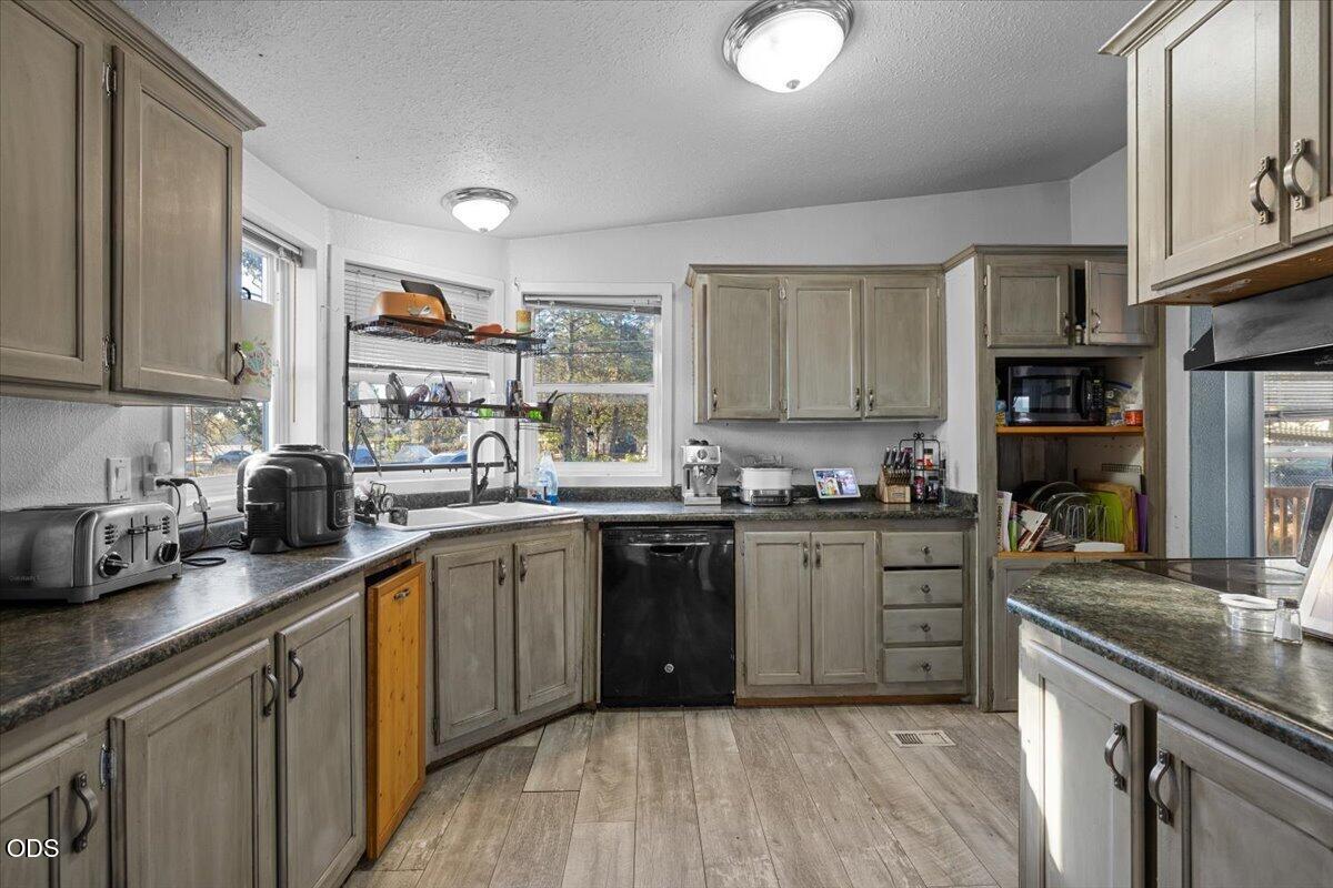 Kitchen with gray cabinets, dark countertops, and a sink beneath wide windows.