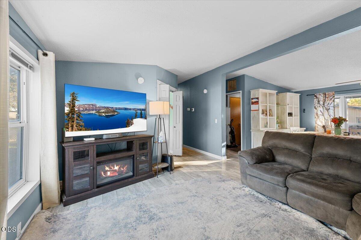 Living room with a gray sectional, blue-gray walls, and a TV above an electric fireplace.