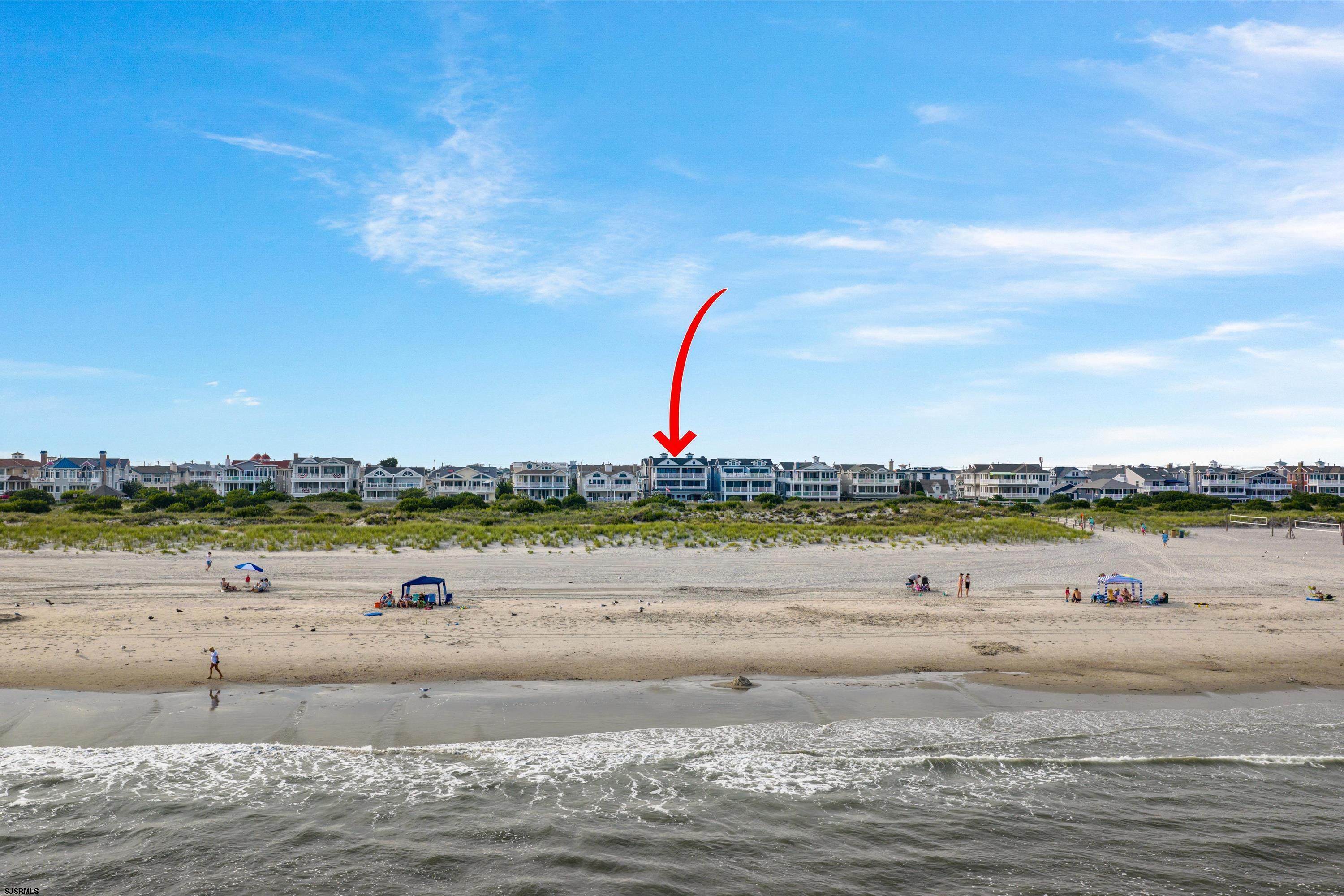 Ocean City beachfront homes across a sandy beach, with a red arrow marking the blue-and-white house.