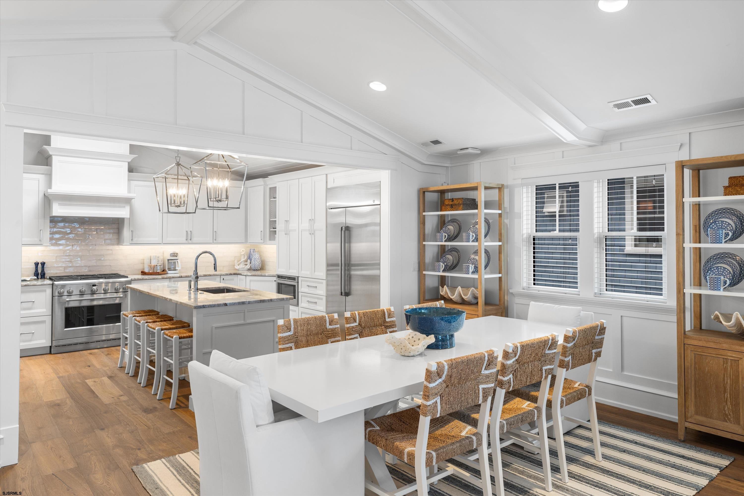 Open-plan kitchen and dining area with white cabinetry, stainless steel appliances, and a large dining table.