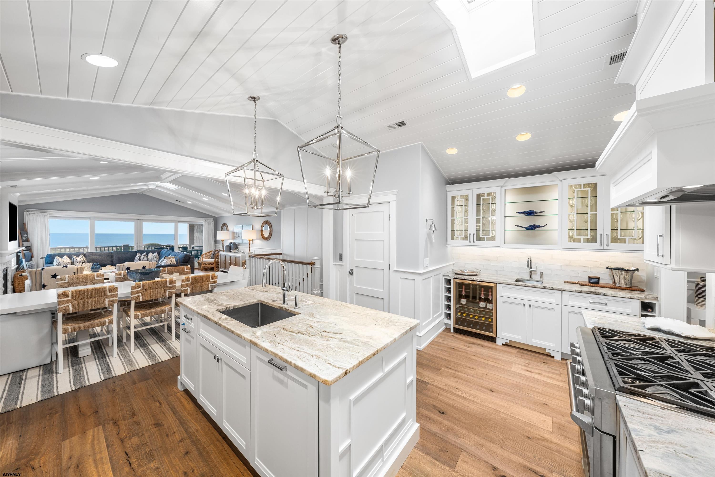 Open-plan kitchen with a large stone island and ocean views through wide windows.