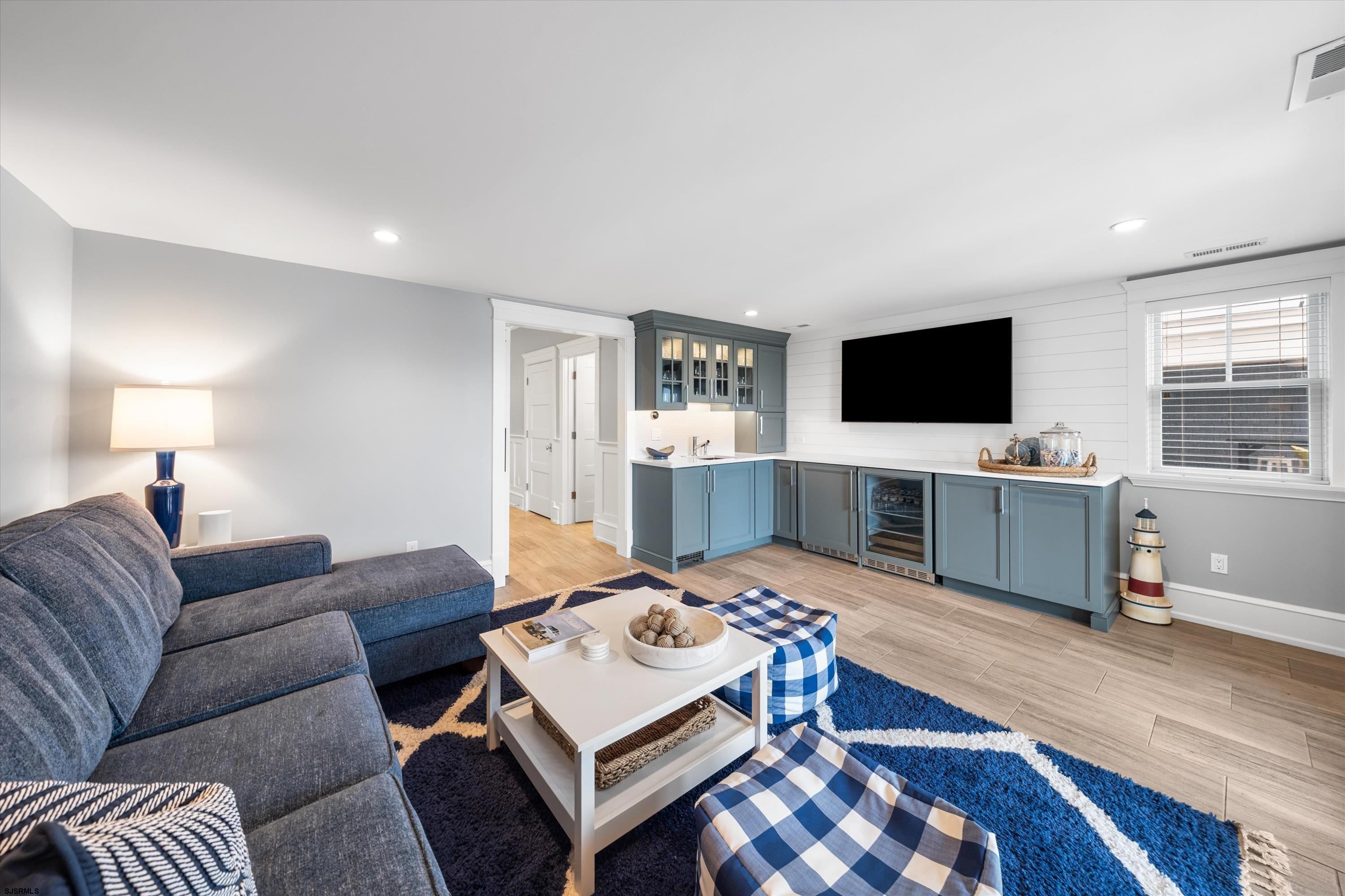 Living room with a gray sectional, blue-and-white rug, and built-in blue-gray entertainment bar.