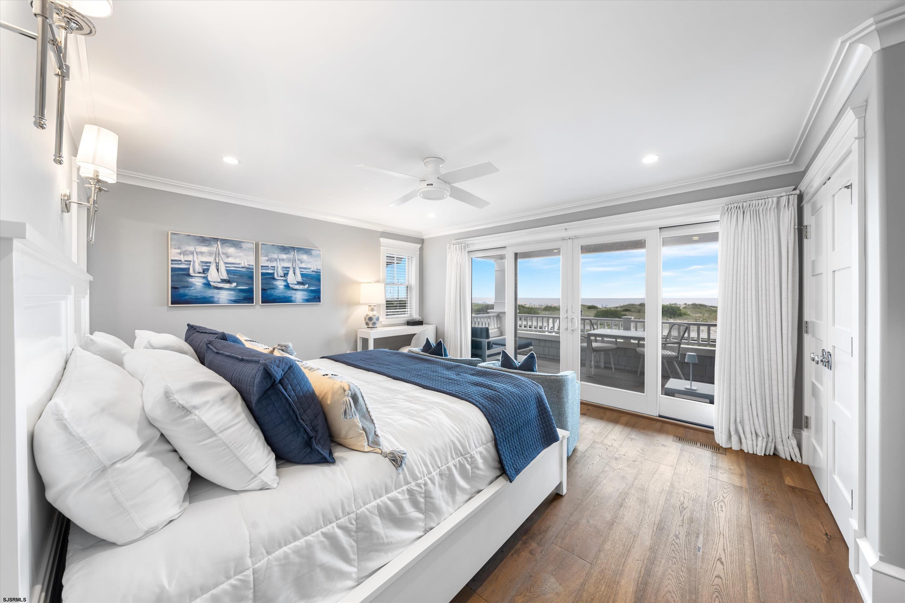 Furnished bedroom with navy bedding and sliding glass doors overlooking the ocean.