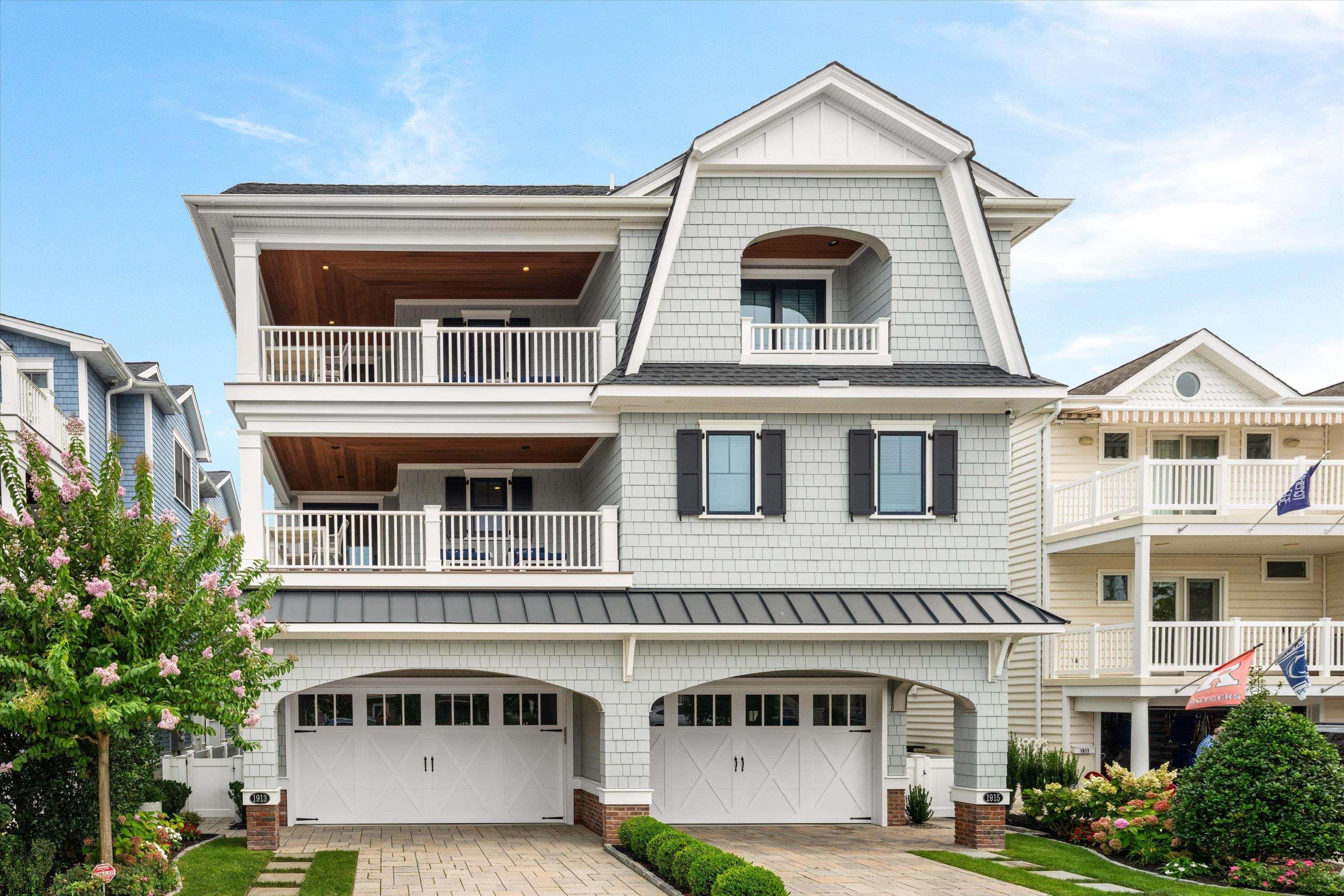 Coastal home with stacked porches, white railings, and two garage doors.
