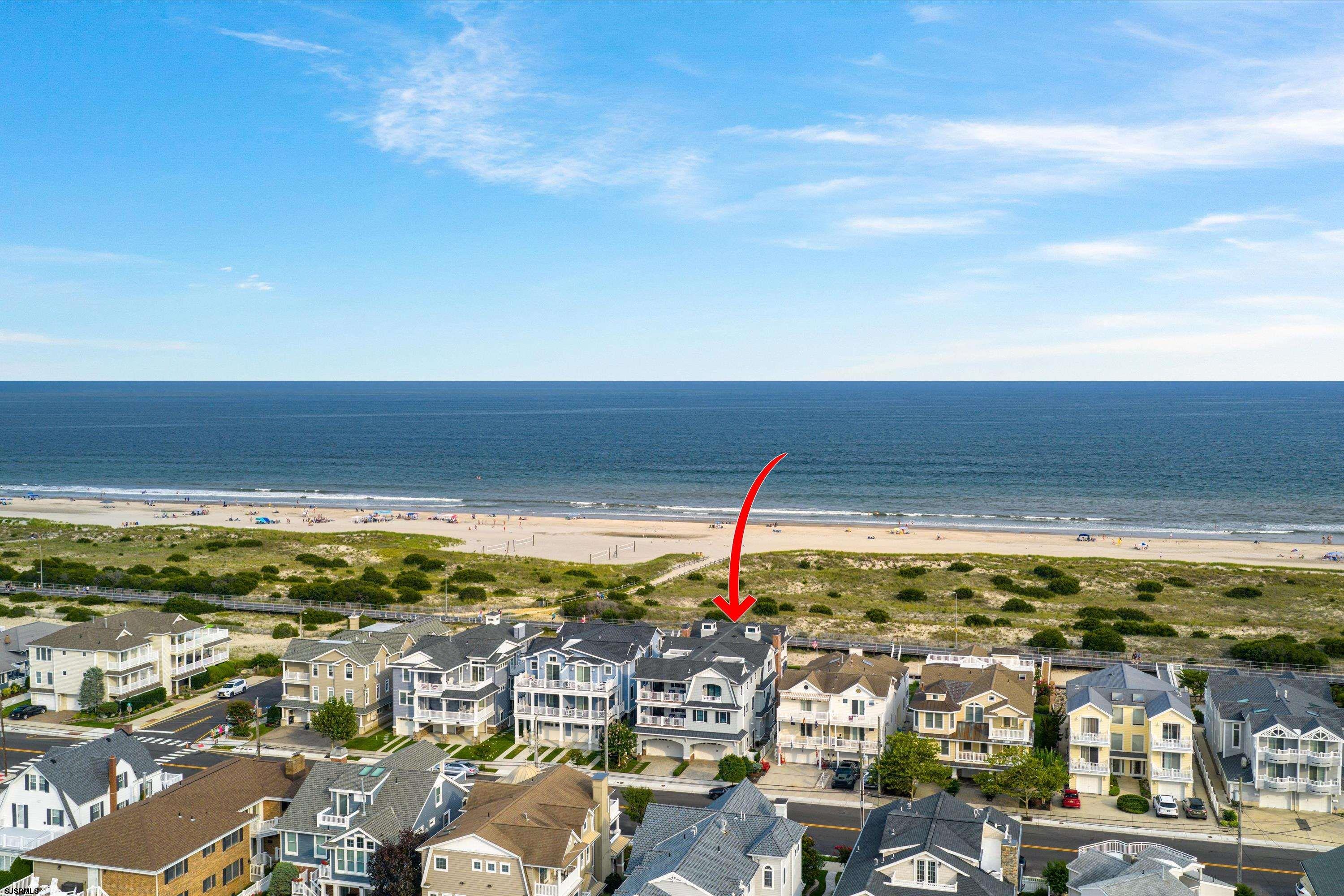 Aerial view of the beach and Ocean City homes, with a red arrow pointing to the featured property.