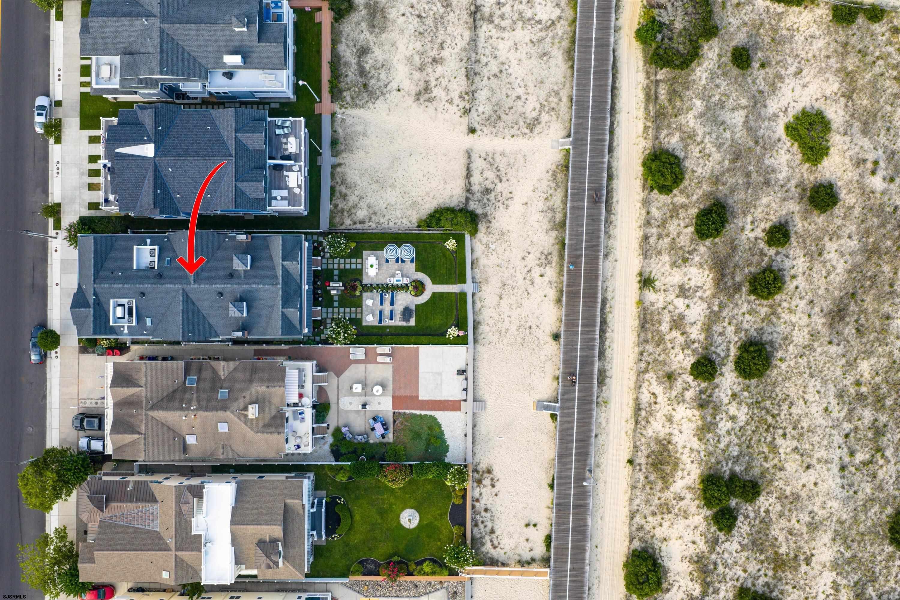Aerial view of the marked beachside residence beside a landscaped patio and boardwalk.