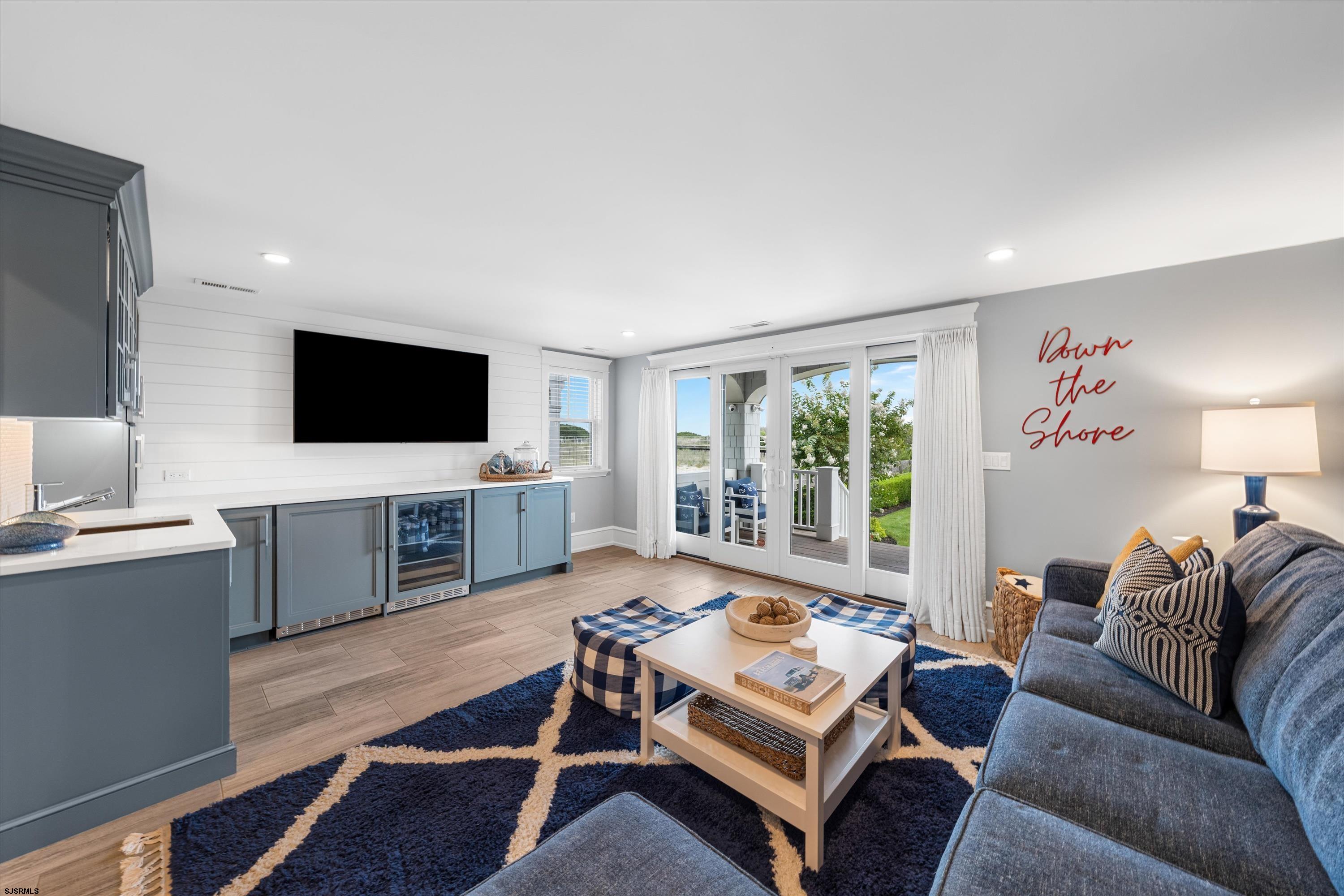 Open-plan living room with blue-gray kitchenette, gray sofa, and glass doors to the patio.