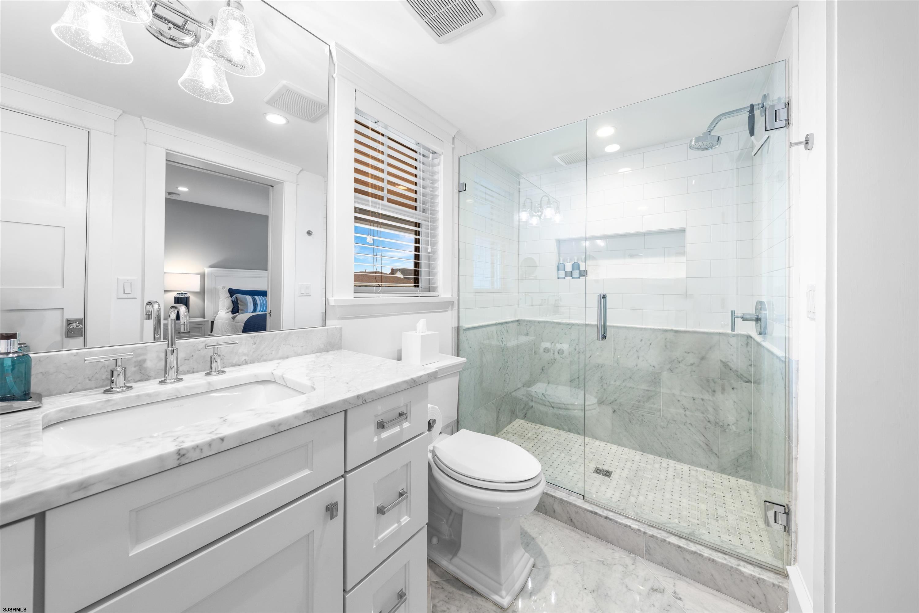 Bathroom with a marble vanity and spacious glass-enclosed shower.