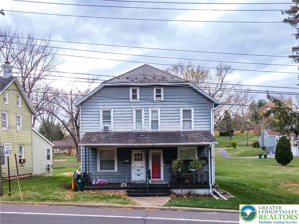 Blue two-story house with a covered porch and red front door.