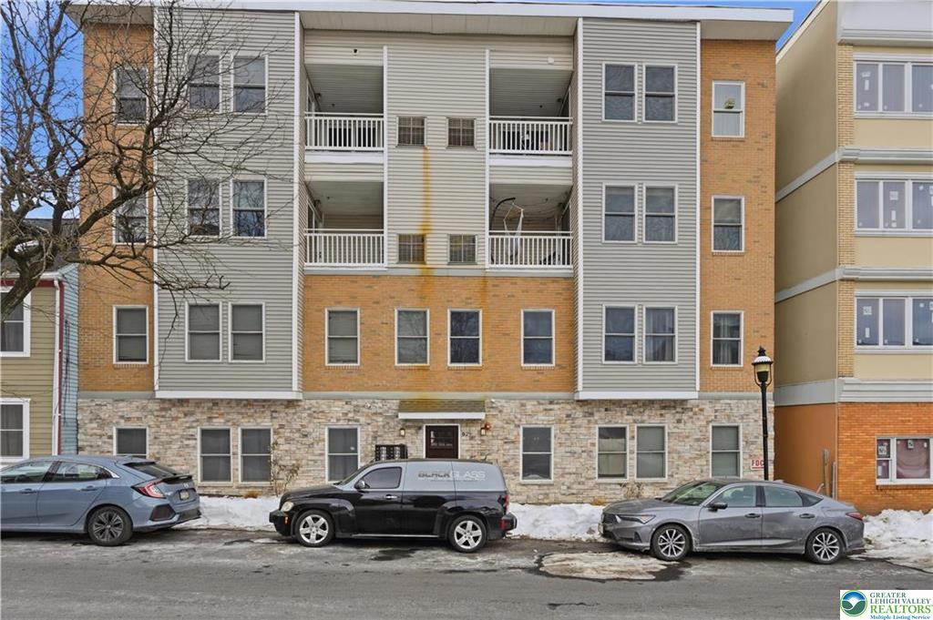 Multi-story Easton apartment building with stacked balconies and cars parked beside a snowy curb.