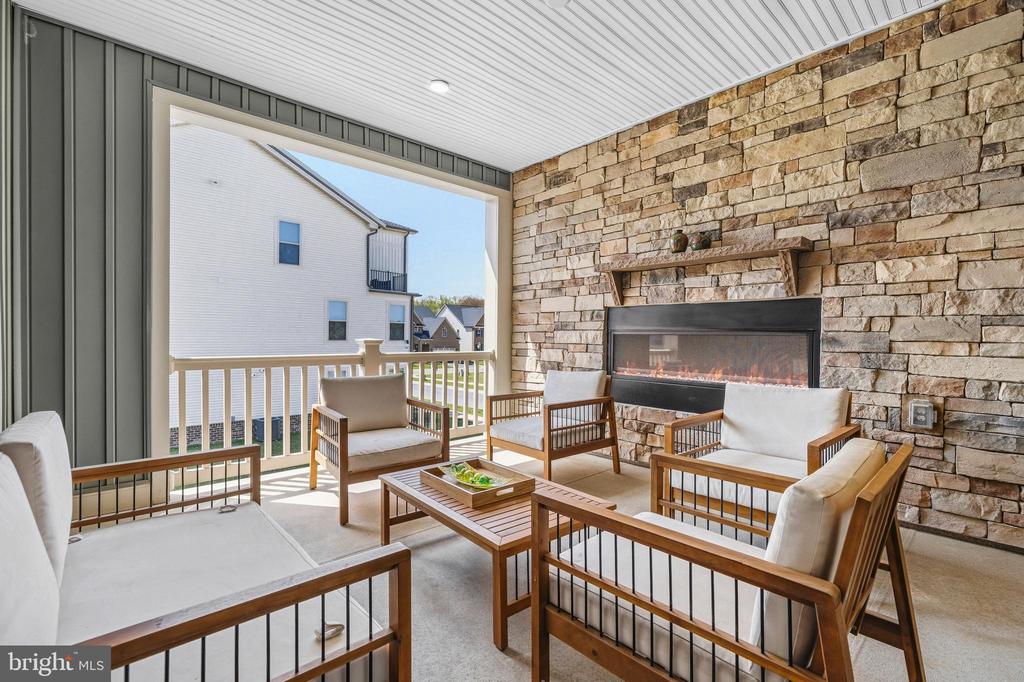 Covered patio with wood lounge seating and a stone fireplace.